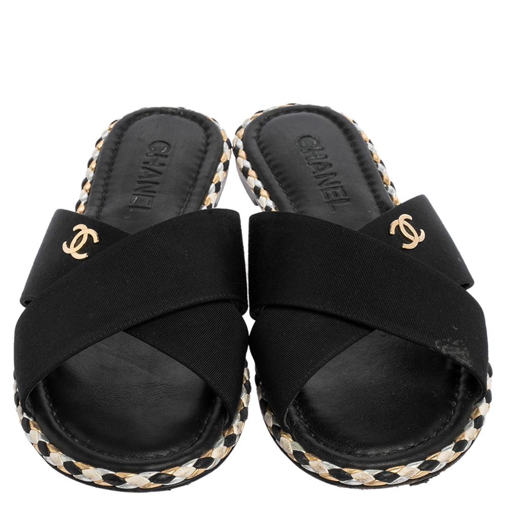 Experience the Chanel charm and comfort with these slides. Crafted with black fabric, they have crisscross straps on the uppers detailed with a CC logo along with beautifully braided trims outlining the pair. The insoles are lined with leather and
