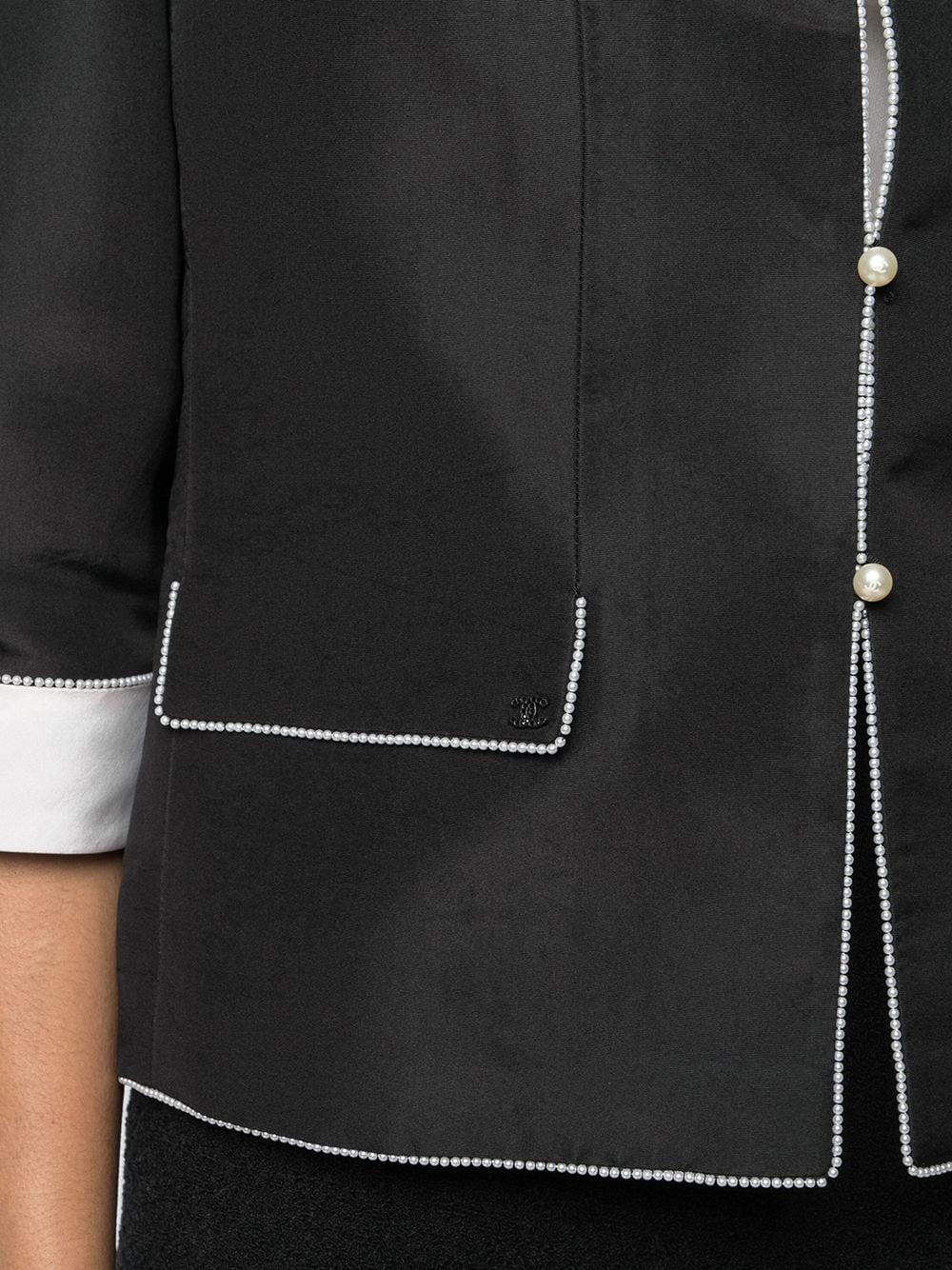 Chanel black silk jacket featuring a faux-pearl trimming, a notched lapels, front faux-pearl button fastening, three-quarter length sleeves, turn-up cuffs, two front flap pockets, a silk lining and a straight hem.
100% silk 
Chanel label size: