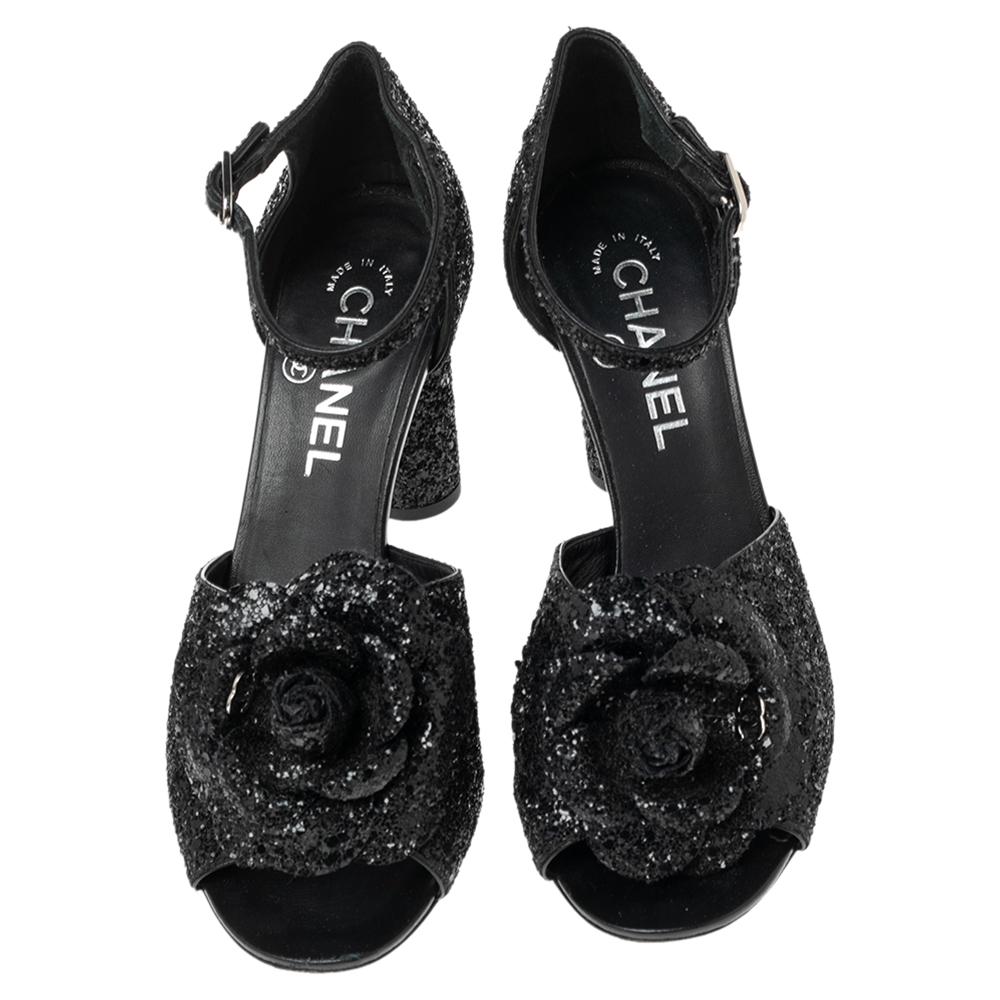 Diese Sandalen sind aus Glitzer für Ihren Komfort gefertigt. Mit diesem fabelhaften Paar von Chanel gehen Sie stilvoll aus. Sie sind in einem klassischen Schwarzton gehalten und mit Kameliendetails und dem CC-Logo auf der Decksohle versehen. Die