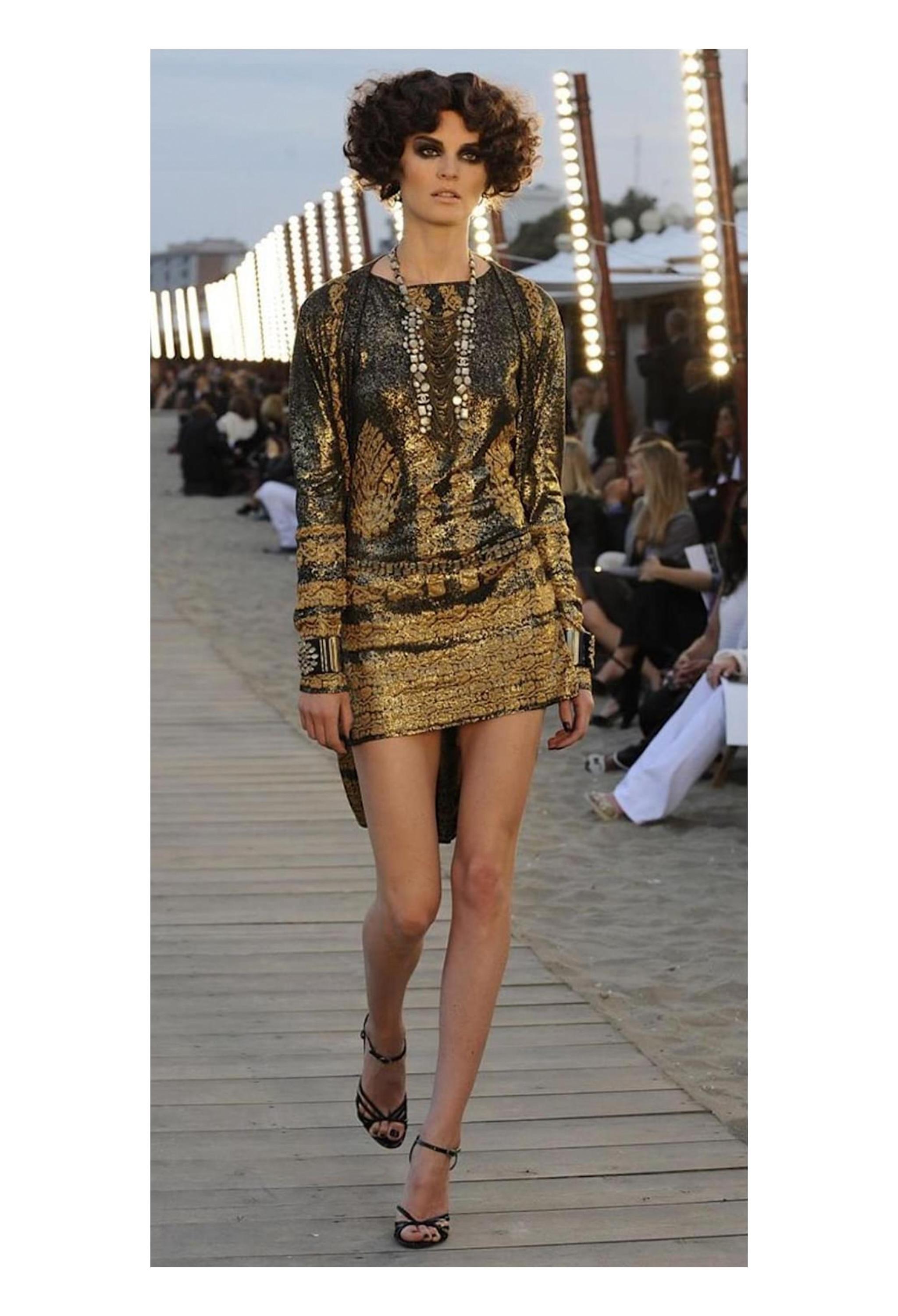 Resurrection Vintage è lieta di offrire un mini abito vintage Chanel by Karl Lagerfeld nero e oro metallizzato della collezione 2010, caratterizzato da un tessuto a maglia jacquard, una silhouette rilassata, senza maniche e con una lunghezza sopra