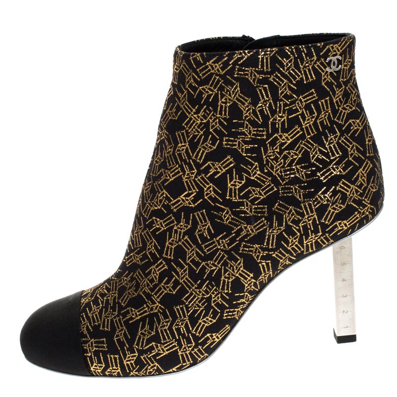 Elevate your style with these unique Chanel ankle boots. Crafted in Italy, they are made from quality fabric and come in lovely hued of gold and black. The printed exterior is beautiful and is enhanced with round cap toes. They are finished with