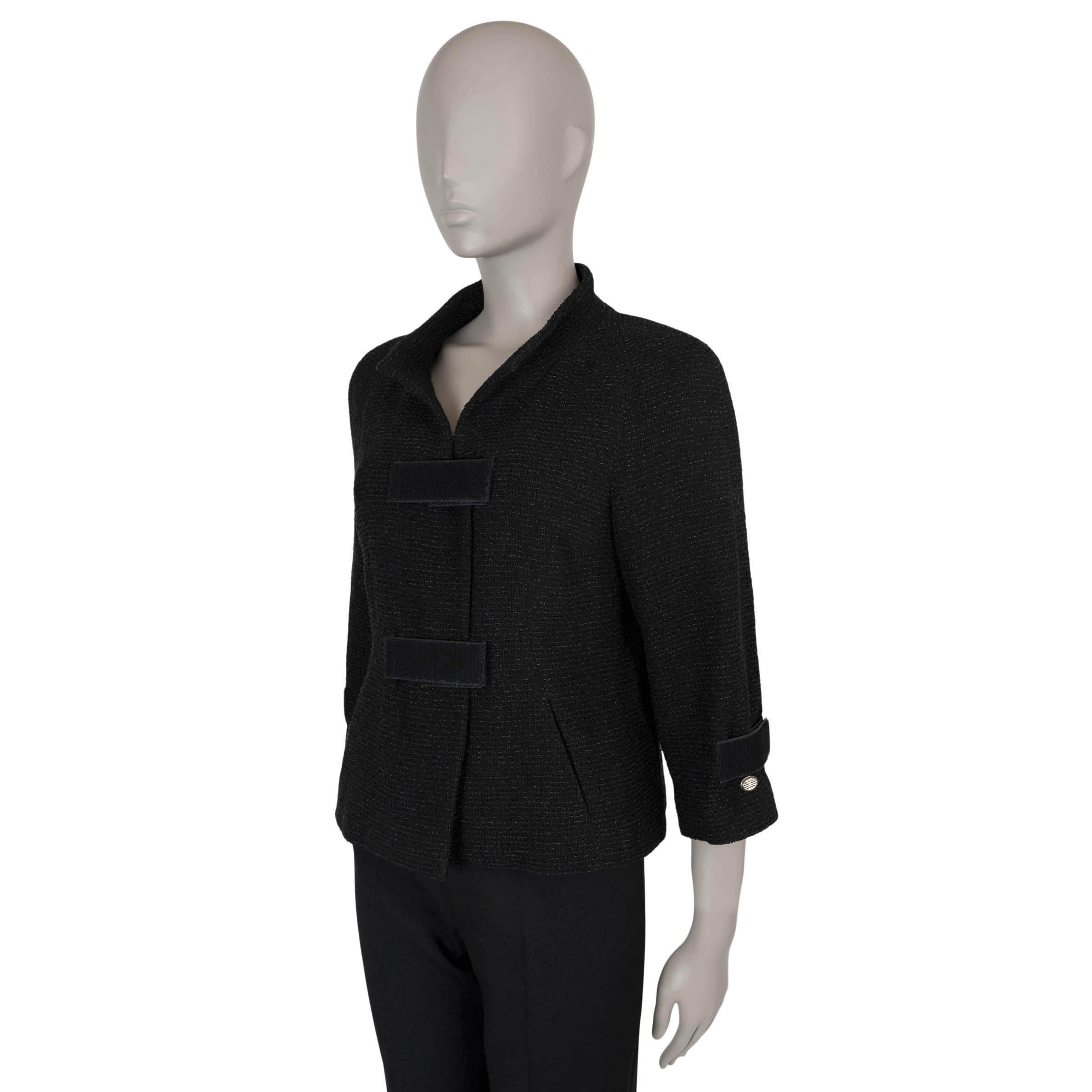 Questa giacca Chanel in tweed nero e grigio, autentica al 100%, è realizzata in una miscela di nylon (72%), cotone (12%), lana (10%) e poliestere (6%). Presenta una silhouette aderente con finto collo, maniche a 3/4 con cinturini in velcro e due