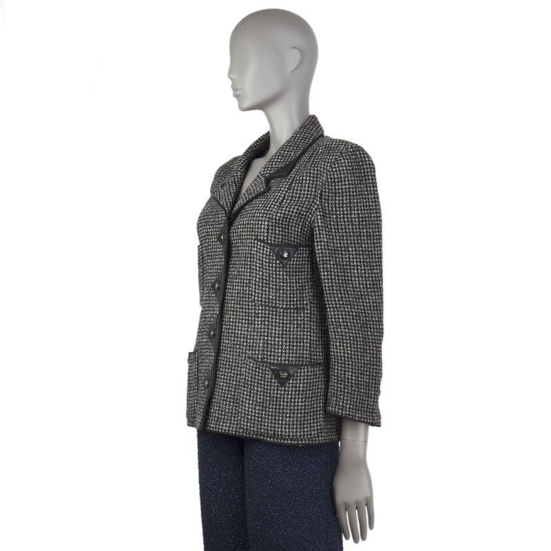 Chanel tweed jacket in black and grey wool blend (assumed as tag is missing). With leather trims, notch collar, four patch pockets on the front with snap closures, buttoned cuffs, aand signature chain around the inside of the hem. Closes with CC