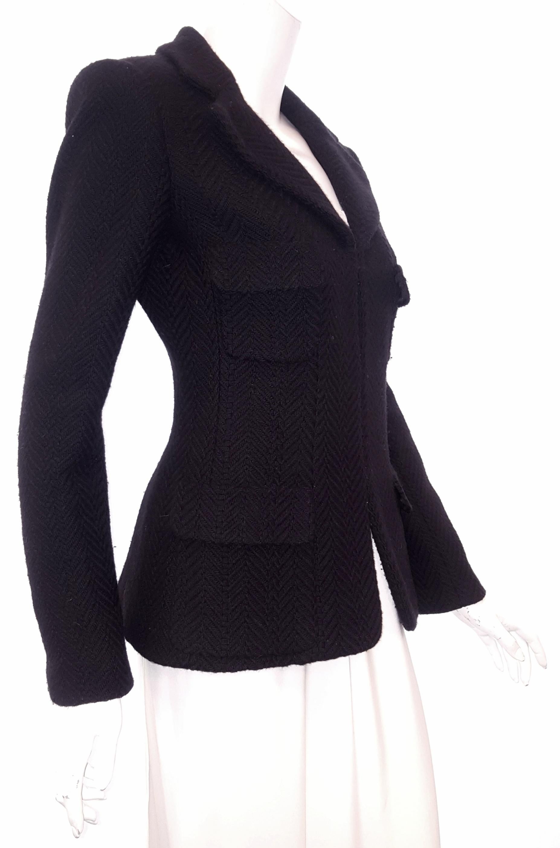 Chanel black wool 2006 Fall Collection classic Chanel herringbone woven tweed jacket incorporates a notch collar.  With four flap pockets at front, and padded shoulders, this jacket is a little bit retro.  Three black buttons, each with a silvertone