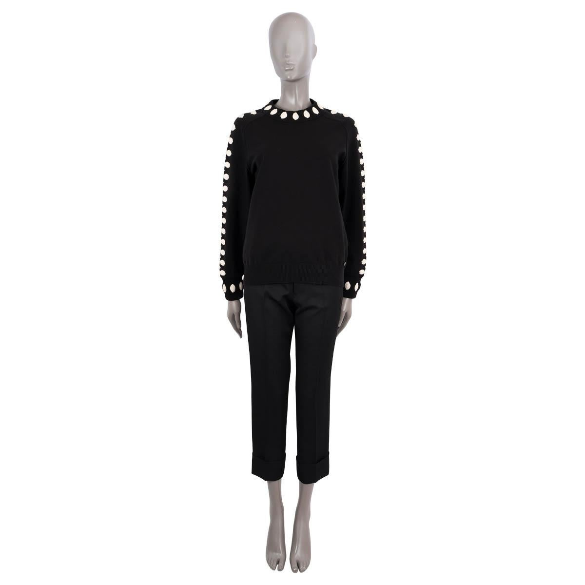 100% authentic Chanel knit sweater in black wool (76%), polyester (18%) and rayon (1%). Features ivory camellia applications, a logo button on the front and  ribbed cuffs. Unlined. Has been worn and is in excellent condition.

2015
