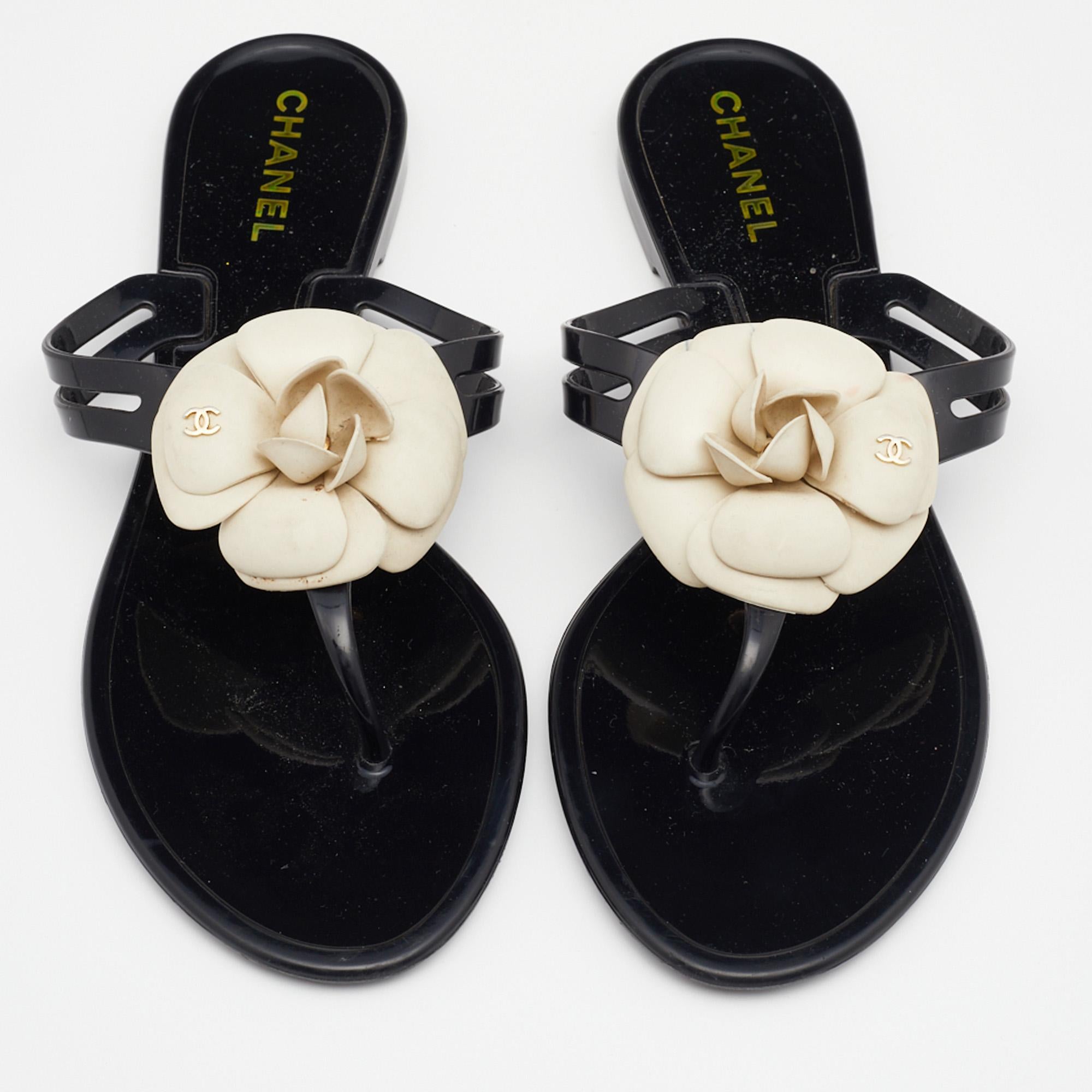 Experience total comfort and iconic style with these thong sandals from the House of Chanel. They are created using black jelly, with a contrasting Camellia motif perched on the upper. These thong sandals are embellished with gold-tone hardware and