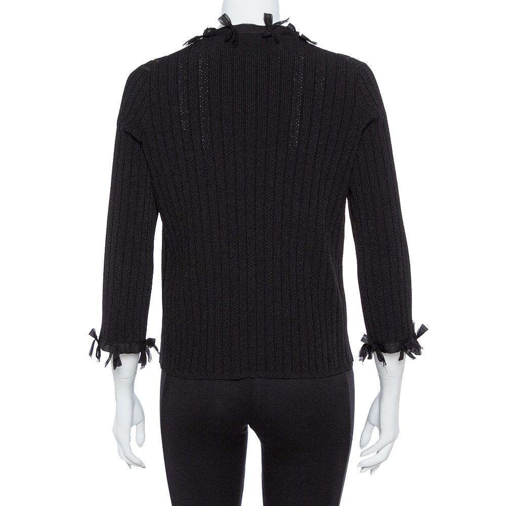 Chanel is known for its impeccable craftsmanship and unique designs. This cardigan is knitted from a blend of quality fabrics in a black hue and accented with dainty bow trims covering the creation's silhouette. Style it with a pencil skirt or