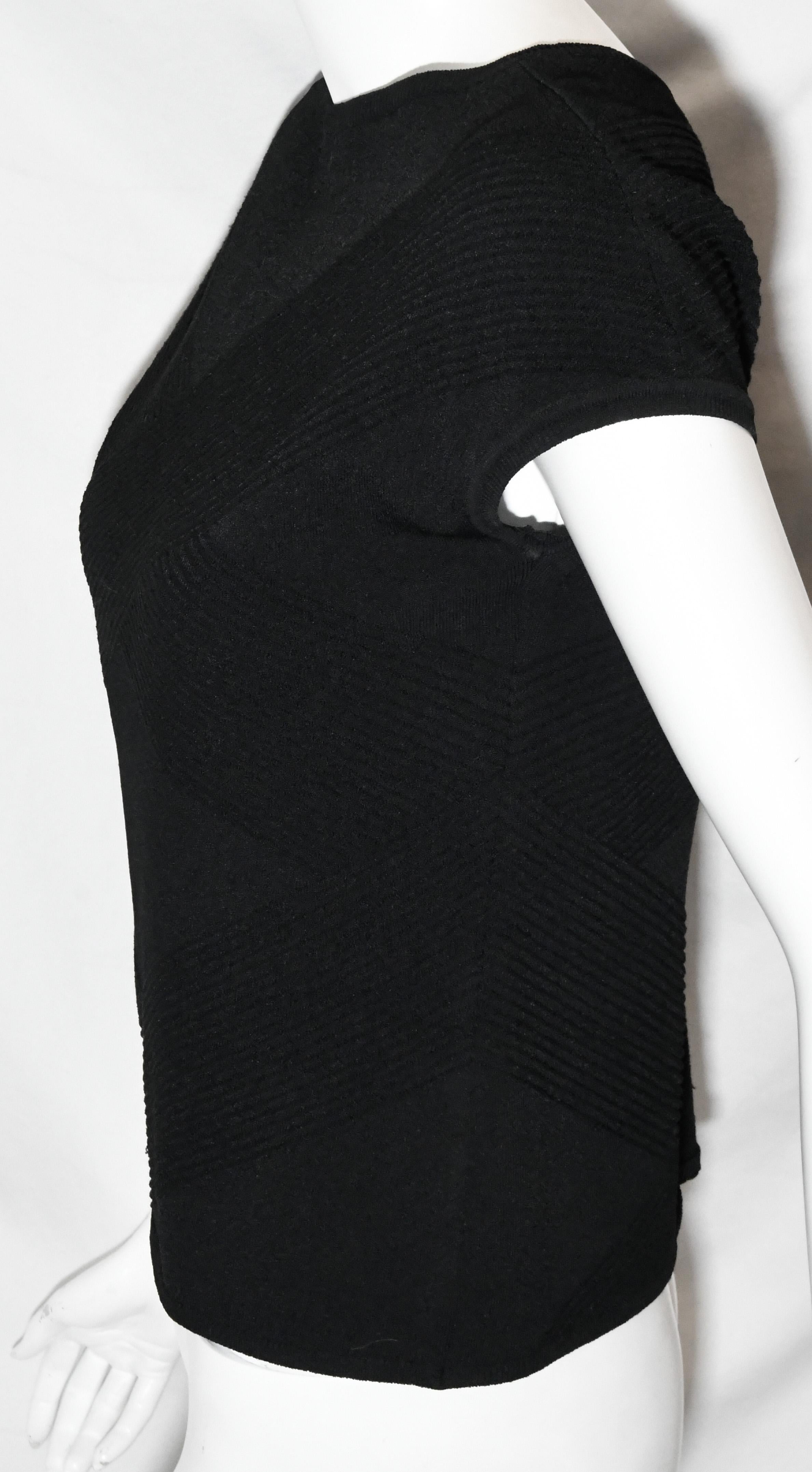 Chanel black knit top is from the 2003 Fall collection.  This classic cap sleeve top con be worn by itself with jeans or under a suit to complement the Chanel look.   This top includes a CC Chanel mini plaque on the hem.  This top is unlined.  This