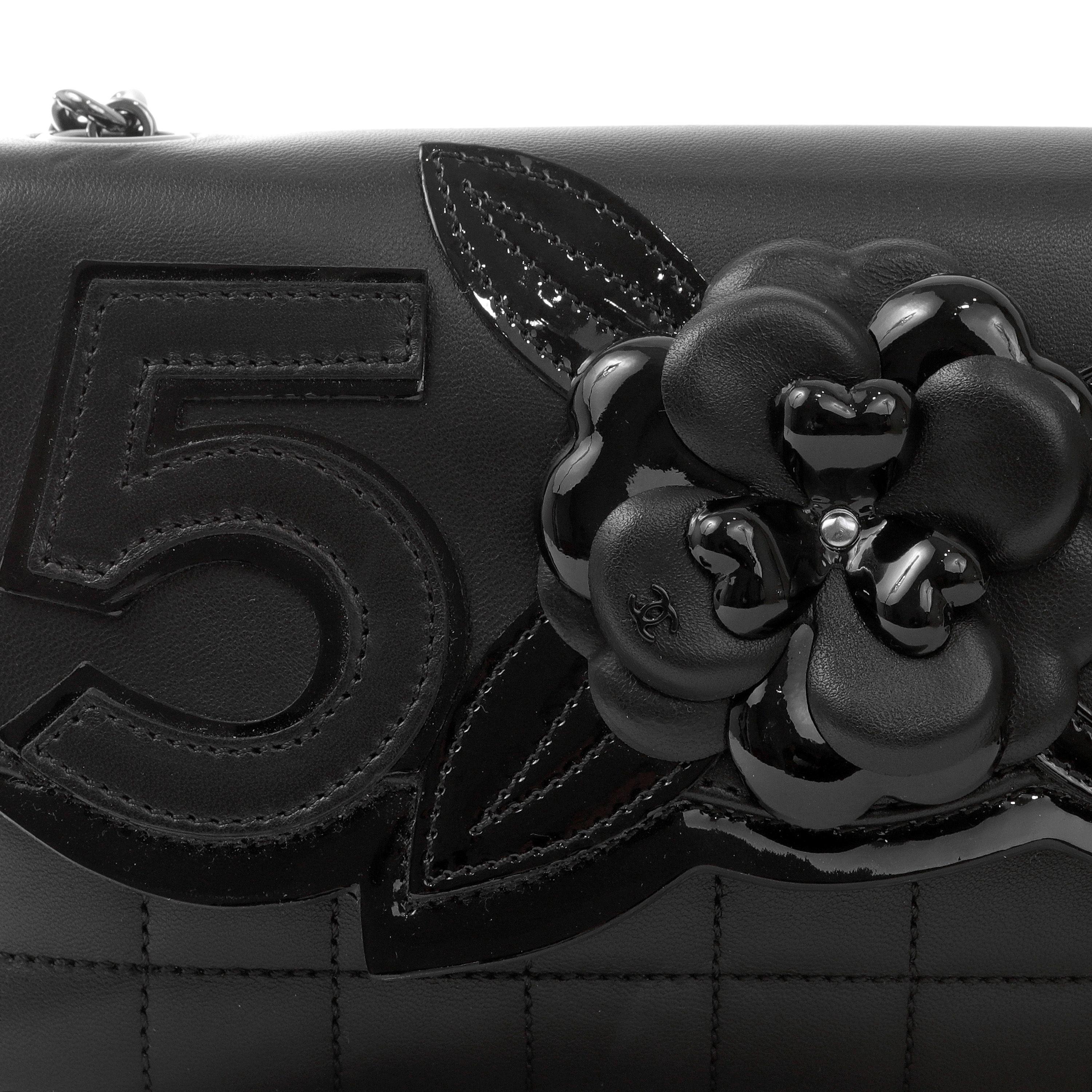 This authentic Chanel Black Lambskin Camellia Flap Clutch is pristine.  Supple black lambskin is stitched in chocolate bar pattern.  Iconic Chanel motifs are incorporated into the flap including the Camellia flower, numeral 5 and interlocking CC. 