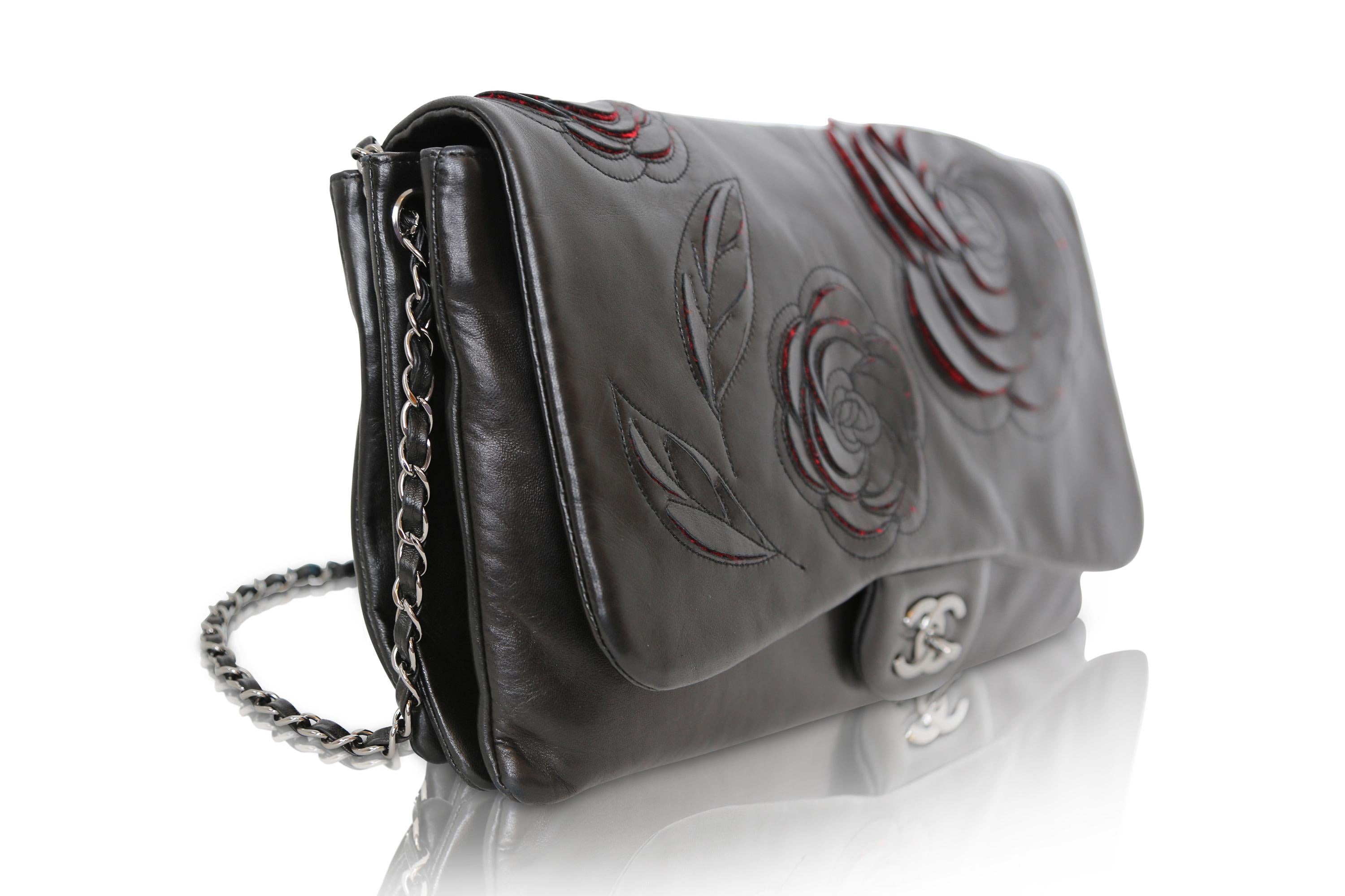 Die Camellia Runway Flap Bag ist aus dem für Chanel typischen schwarzen Lammleder gefertigt und verfügt über ein elegantes, silberfarbenes, ineinandergreifendes CC und ein leuchtend rotes Innenfach aus Stoff mit mehreren praktischen Fächern. Der