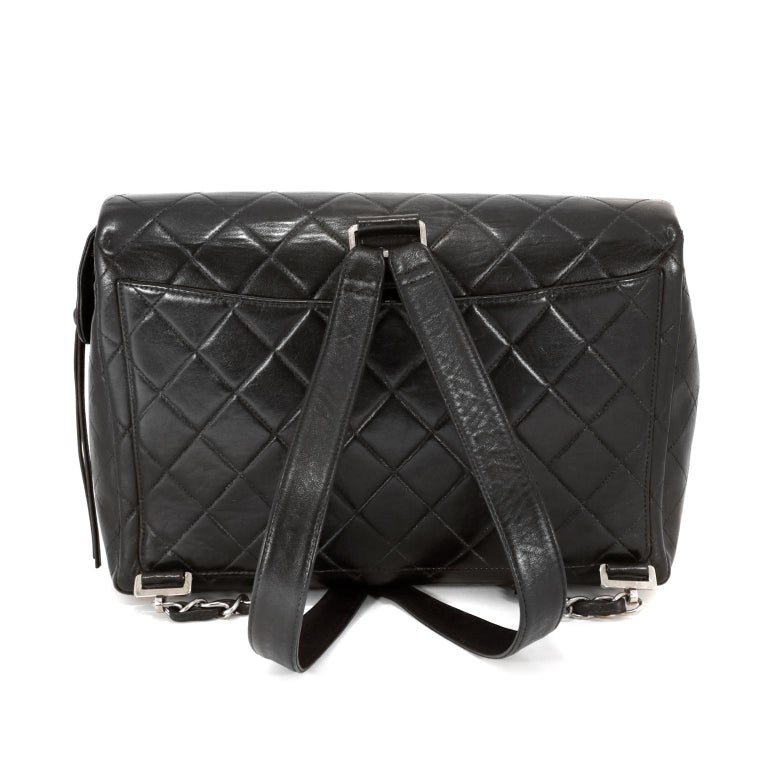 This authentic Chanel Black Lambskin Classic Flap Backpack is in very good vintage condition.  A cool unisex spin on the timeless classic flap bag, the backpack is a roomy hands-free version.  
Black lambskin is quilted in signature Chanel diamond