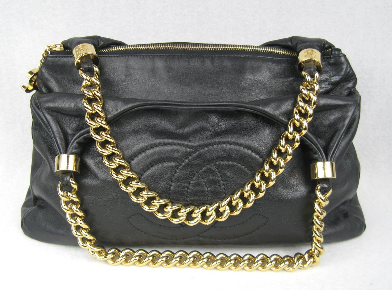 Stunning black Chanel leather with thick gold tone chain. front logo Middle zippered closure with 2 outside compartments with snap closures. Measures 14 inches wide x 9 inches high. 8 inch drop on chain. Purchased at Neiman Marcus, still has prices