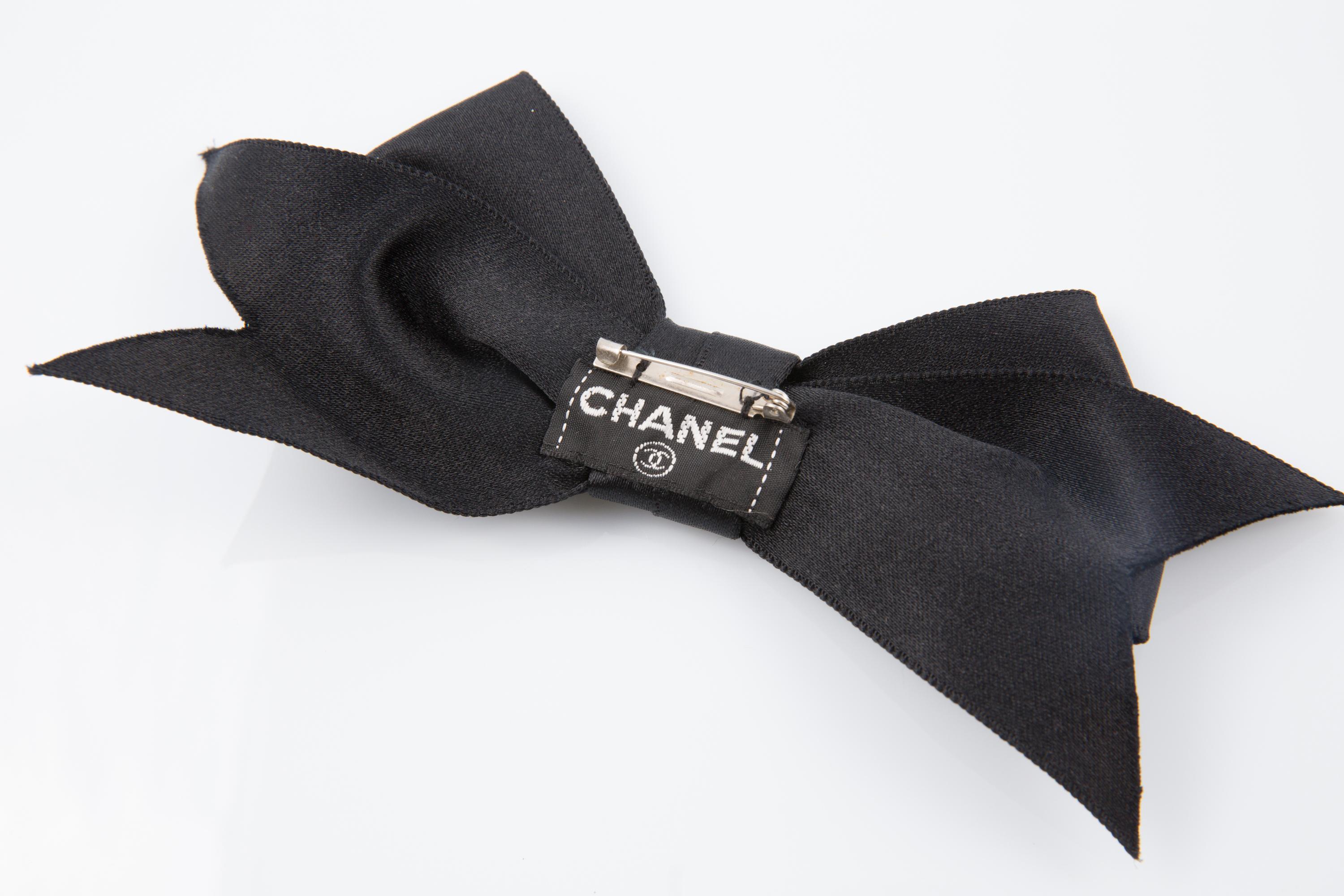 Broche de pajarita de satén de seda Chanel Negro con cierre de pasador y etiqueta trasera con el logotipo. 
Alrededor de la década de 2000. Fabricado en Francia
Longitud maxi:19 cm (7,4 pulg.)
Anchura central: 3 cm (1,18 pulg.) 
Buen estado vintage.