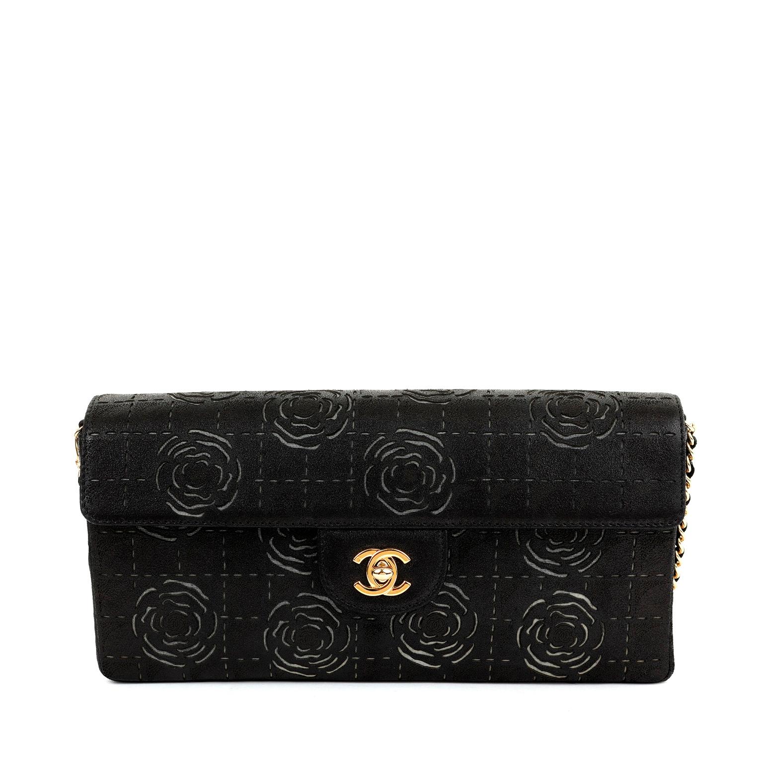 This authentic Chanel Black Laser Cut Camellia Baguette Bag is in pristine condition.  East West configured flap bag style has subtle cut outs in signature Chanel camellia flowers.  Gold interlocking CC twist lock secures the flap.  Elegant chain