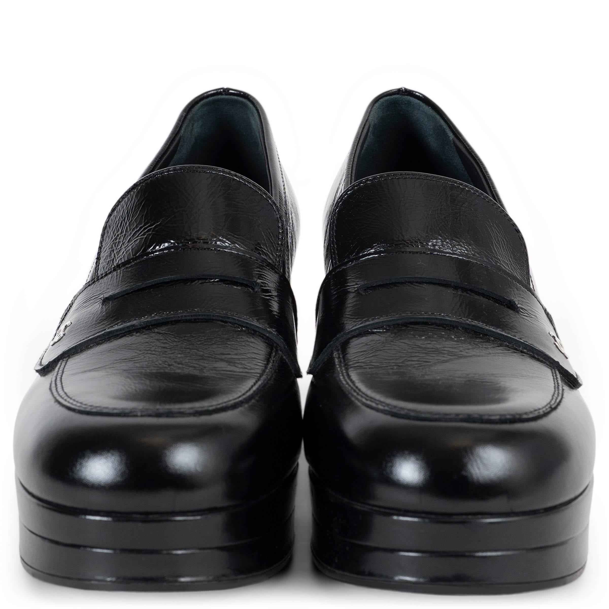 Questa décolleté Chanel, autentica al 100%, è realizzata in pelle di vitello nera lucida con una finitura elegante e brillante. Con una punta arrotondata, presenta un classico cinturino da penny loafer sul davanti, ornato da un discreto logo CC