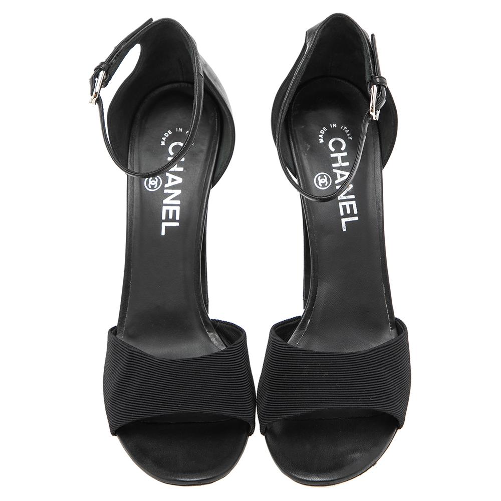 Take each step with style and panache in these sandals from the House of Chanel. Crafted from black leather and canvas on the exterior, they are designed with pearl-embellished heels and a buckled ankle strap. Wear these sandals with your attire and