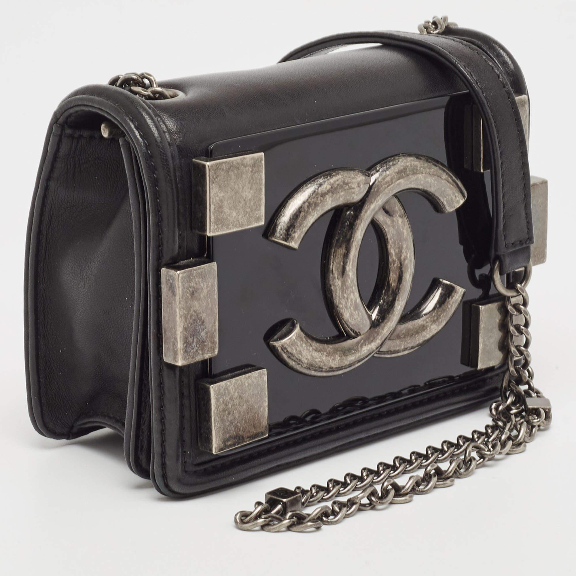 The Chanel Brick Flap Crossbody Bag is a chic accessory that seamlessly blends classic elegance with modern design. Crafted from luxurious black leather and adorned with a sleek plexiglass panel, it features a compact silhouette, a flap closure, and