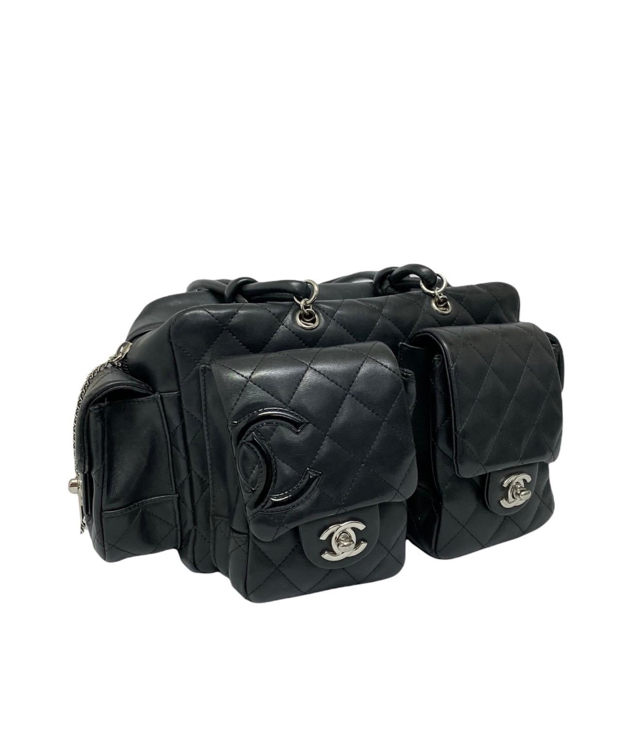 Chanel Cambon Reporter model bag in black quilted calfskin and with silver hardware.  It has a central opening with zip closure, and the interiors are lined with a fuchsia fabric and also has internal pockets.  The bag has five external pockets,