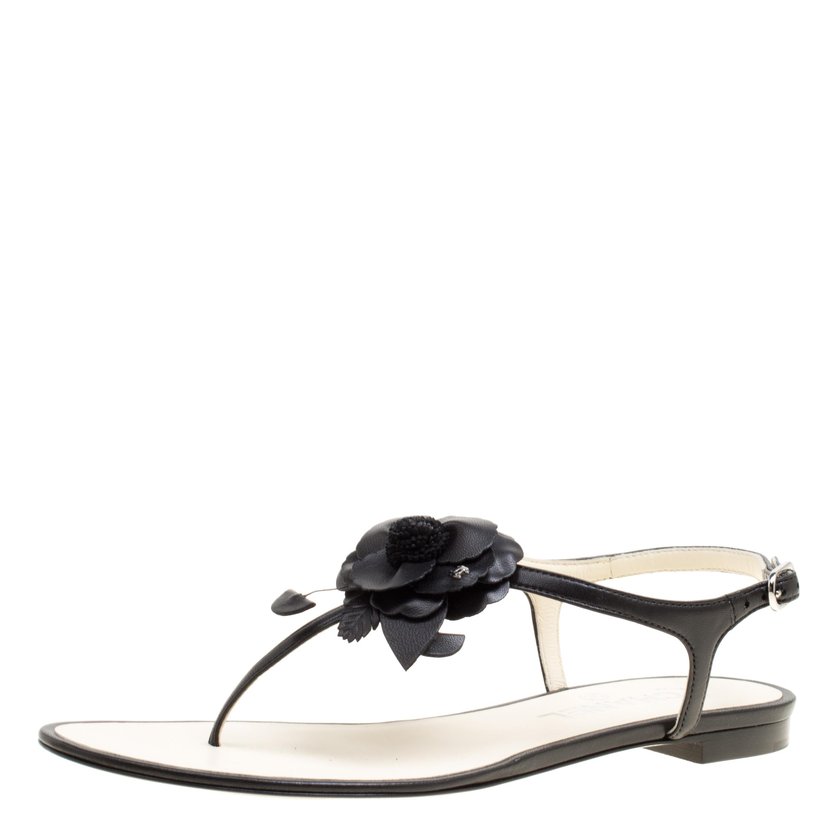 This summer, give the Chanel touch to your outfit by stepping out in these thong sandals. Crafted from black leather, this pair features a t-strap and buckle fastening at the ankles. The pair is complete with a CC-adorned Camellia flower on the