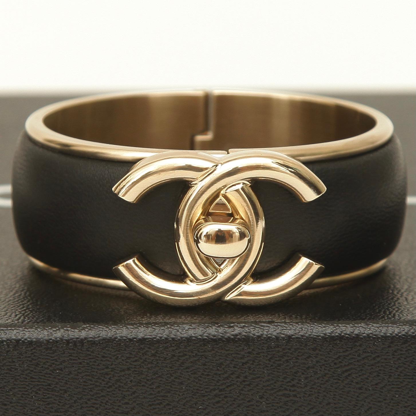 GUARANTEED AUTHENTIC CHANEL 21S BLACK LEATHER CUFF

Details:
- From the 2021 spring collection.
- Wider version.
- Black leather.
- Gold-tone hardware.
- CC turlock closure.
- Signature plaque found inside cuff.
- Comes with dust bag and bag.

Size