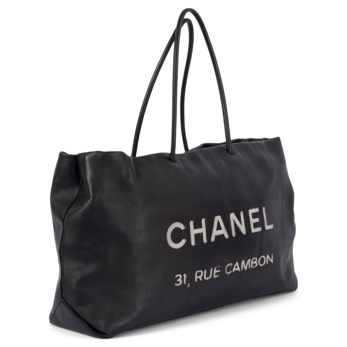 100% authentic Chanel Essential large tote bag in smooth black calfskin with slightly faded off-white stitched canvas logo lettering. Opens with a zipper on top and is lined in black & off-white printed nylon with one bit zipper pocket against the