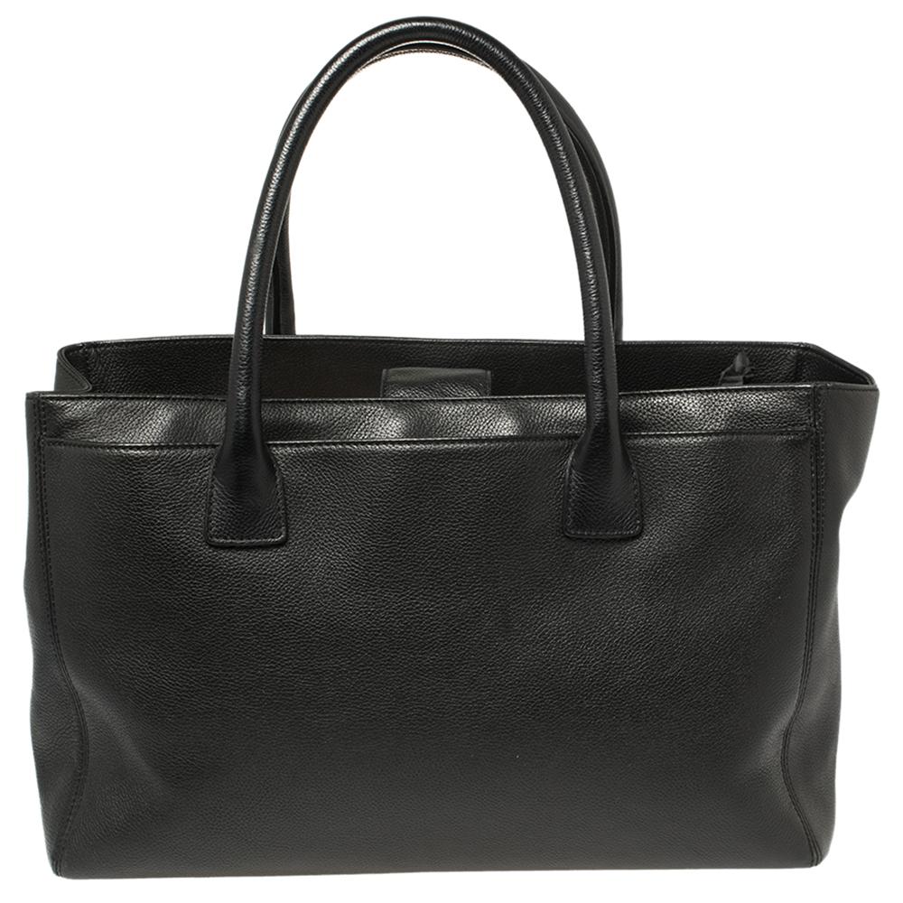 This Cerf tote from Chanel is a perfect blend of practicality and style. It features a black leather construction that is enhanced with a silver-tone CC logo on the front and dual top handles. It is equipped with a spacious interior that can easily