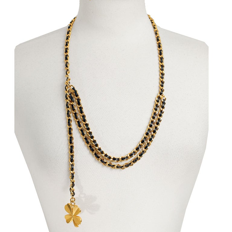 This authentic Chanel Black and Gold Chain Clover Belt Necklace is in excellent condition.  Versatile and classic- a must have for any collection. 
Gold chain is woven together with black leather.  A gold clover dangles decoratively from one end. 