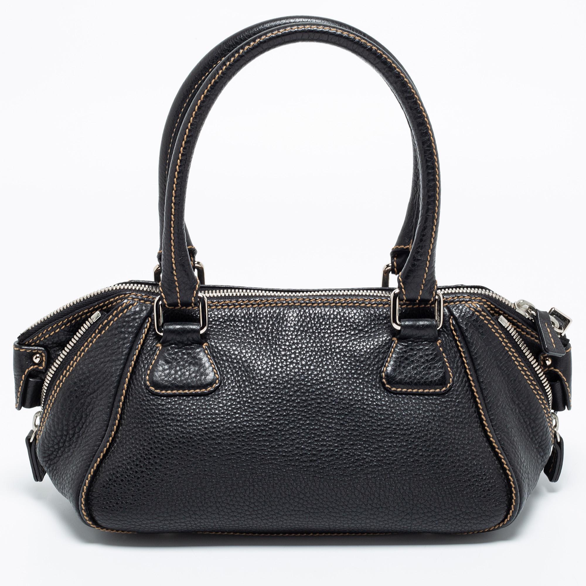 Make this sophisticated bag by Chanel your own! It is made from black leather and features a tassel detail on the side. Dual handles and a zip closure reveal a spacious fabric interior to house your essentials. This one is the perfect day