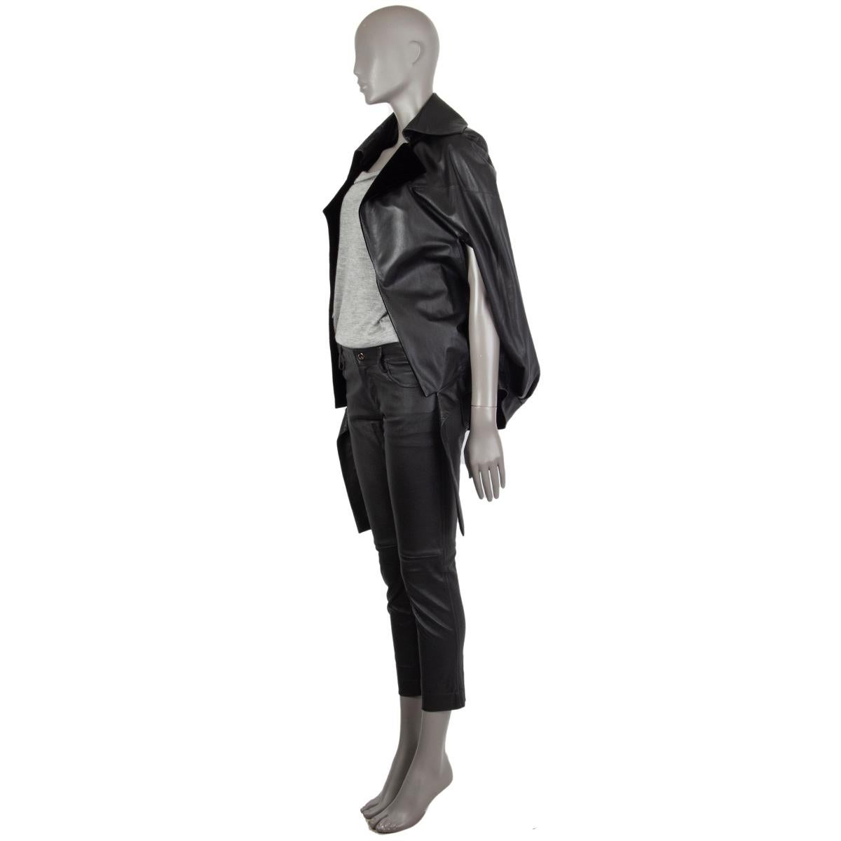 Chanel cpae in black calf skin with velvet trims in black rayon (98%) and silk (2%). Features a notched collar, arm slits that can be closed with concealed zippers, and pleats coming from the waist up. Ties on the front at the waist. Lined in black