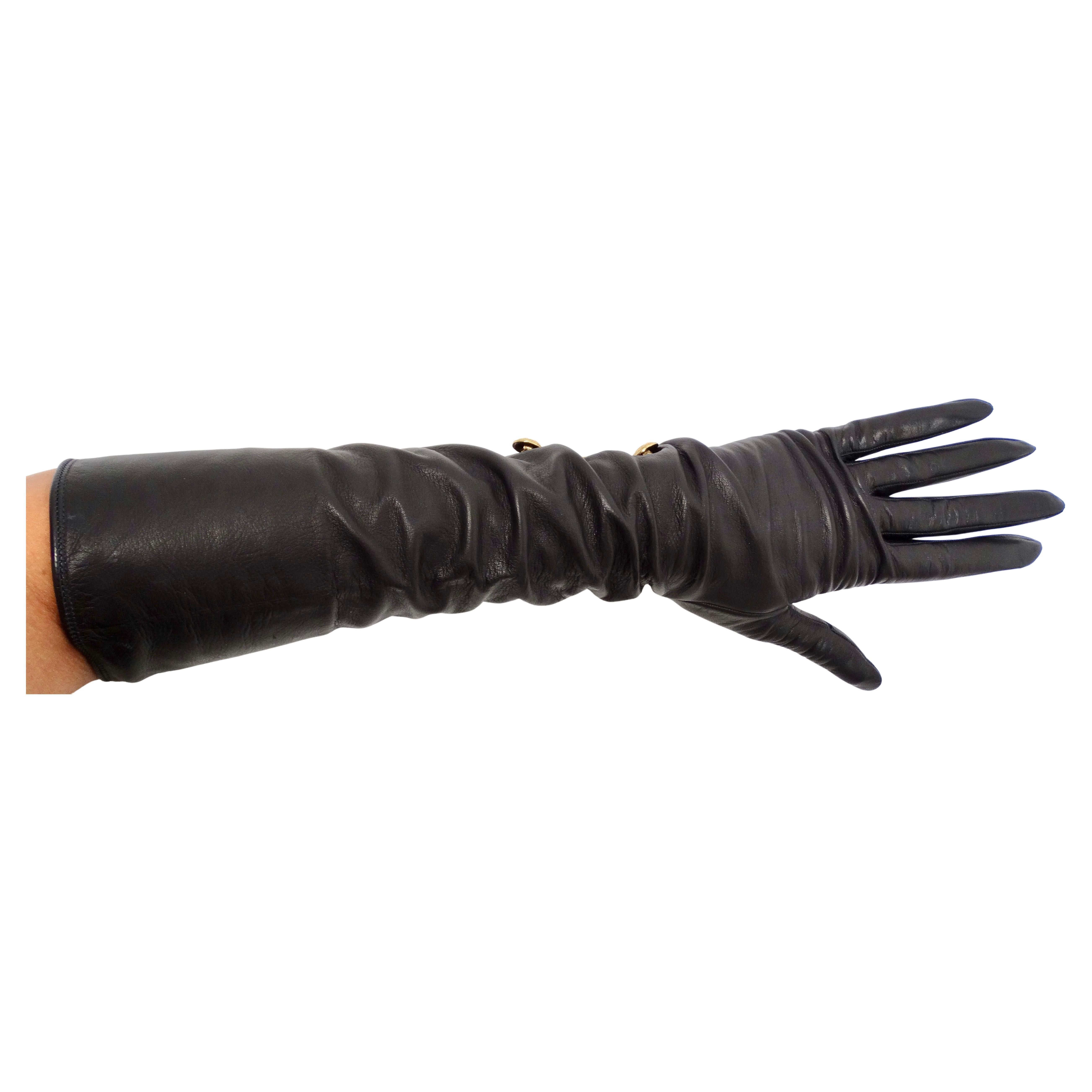 I guanti lunghi in pelle nera Chanel con bottoni CC a incastro degli anni '90 incarnano un'eleganza senza tempo e uno stile sofisticato. Realizzati in pelle nera liscia, questi guanti si estendono con grazia fino ai gomiti, offrendo protezione e