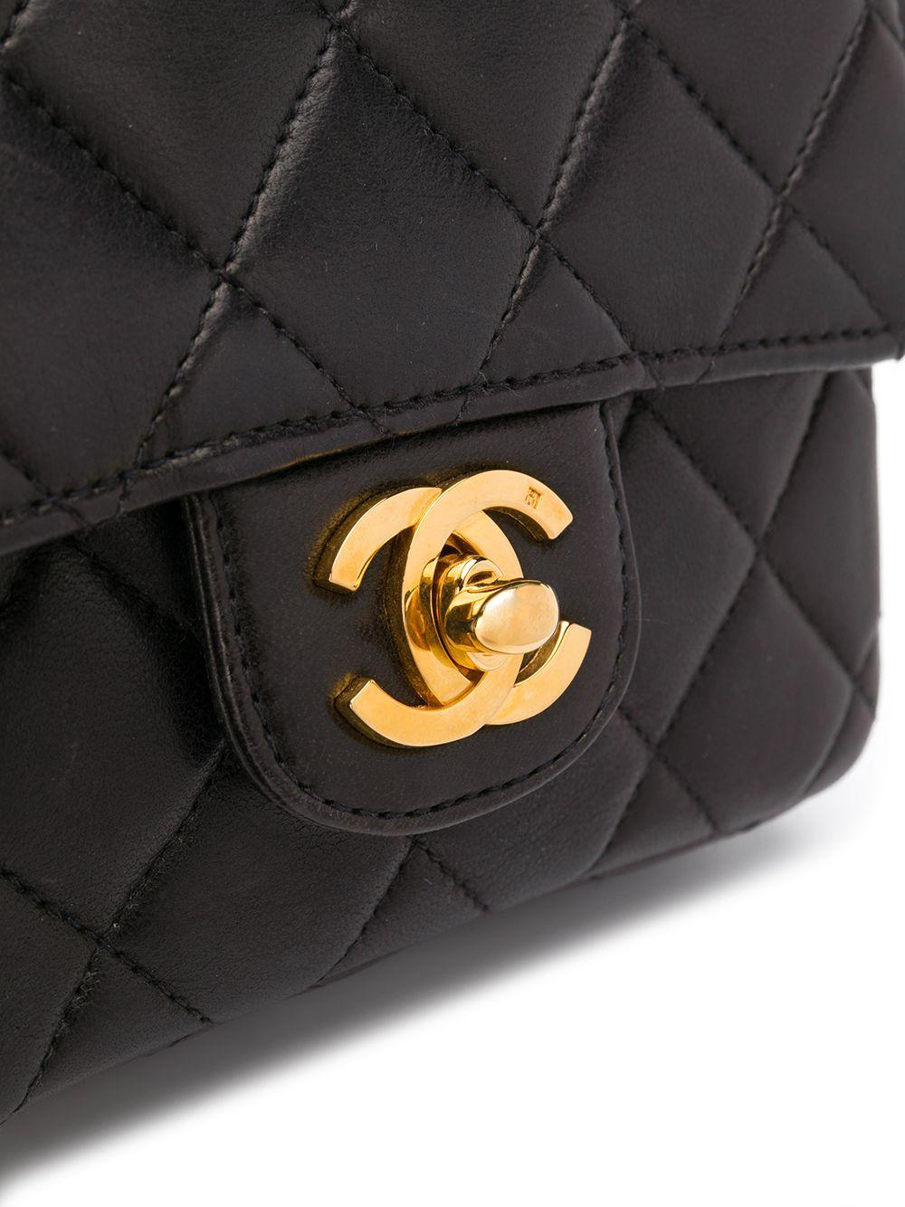 Crafted in France from pure black lambskin leather, this pre-loved Chanel mini kelly bag features a soft quilted exterior, a rear patch pocket and a single rolled top handle for an added touch of sophistication. The foldover top of the bag opens