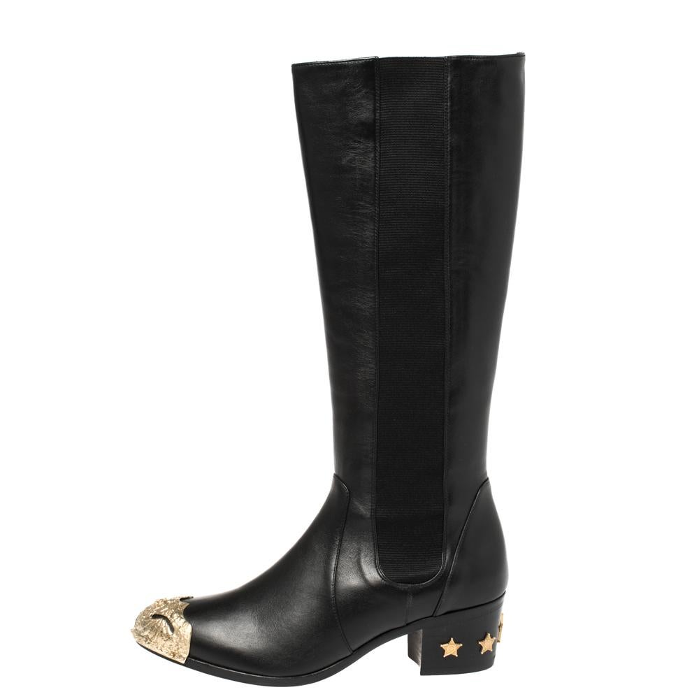 To complement your unparalleled style, Chanel brings you these gorgeous knee-length boots that come flowing with high-fashion. The pair is crafted from black leather and designed with CC metal cap toes and stars decorated on the short heels. Team