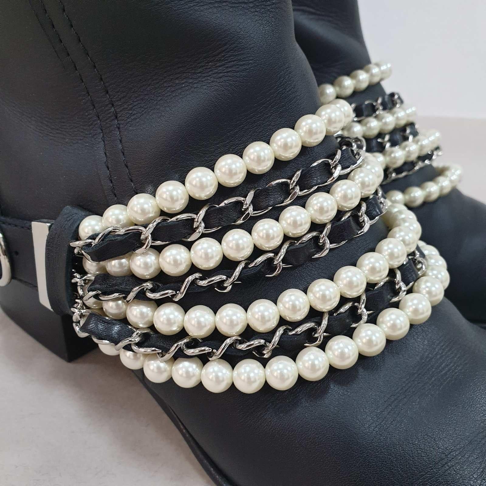 Creations as fashionable as this pair of knee-length boots from Chanel deserve to be in every woman's closet. 
These designer boots have been created using black leather and highlighted with layers of faux pearls and woven chains on the
