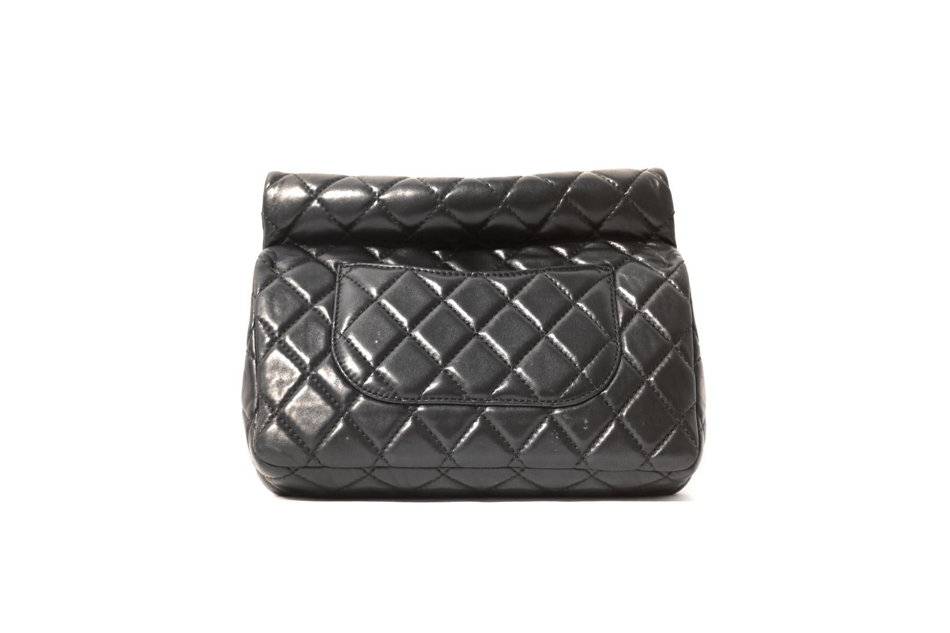 This authentic Chanel Black Leather Rolled Handle Reissue Clutch is in excellent condition.  From the 2012 collection, this unique hand-held style combines the Chanel classic silhouette with an appealing twist.  
Black leather is quilted in