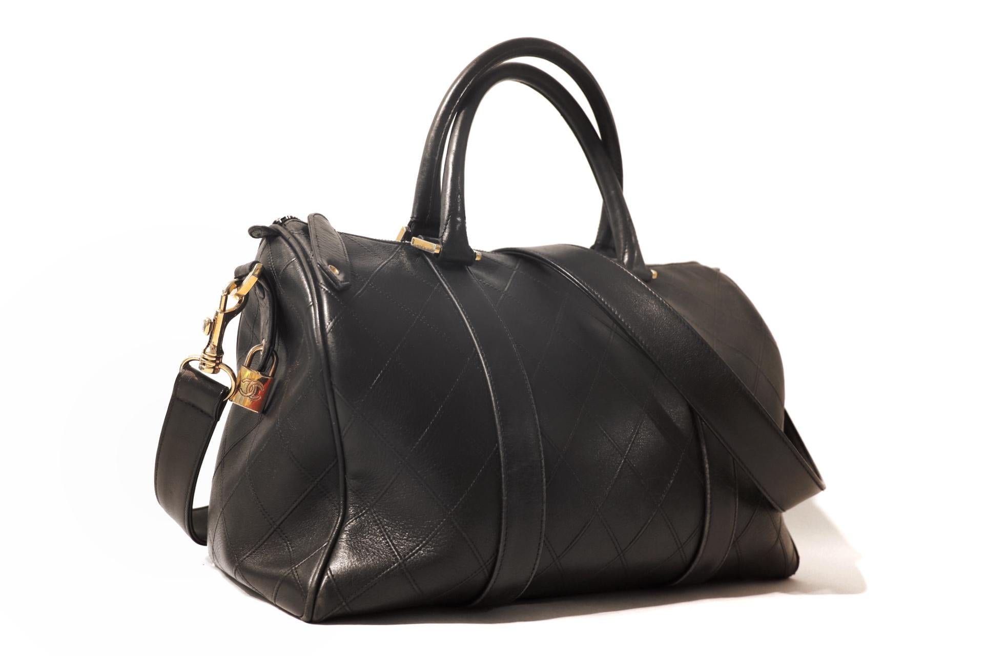 This authentic Chanel Black Leather Vintage Speedy Bag is in excellent condition.  A timeless piece from the early 1990’s, it has maintained its status as a true classic.  
Black leather duffel style handbag is flat stitched in signature Chanel