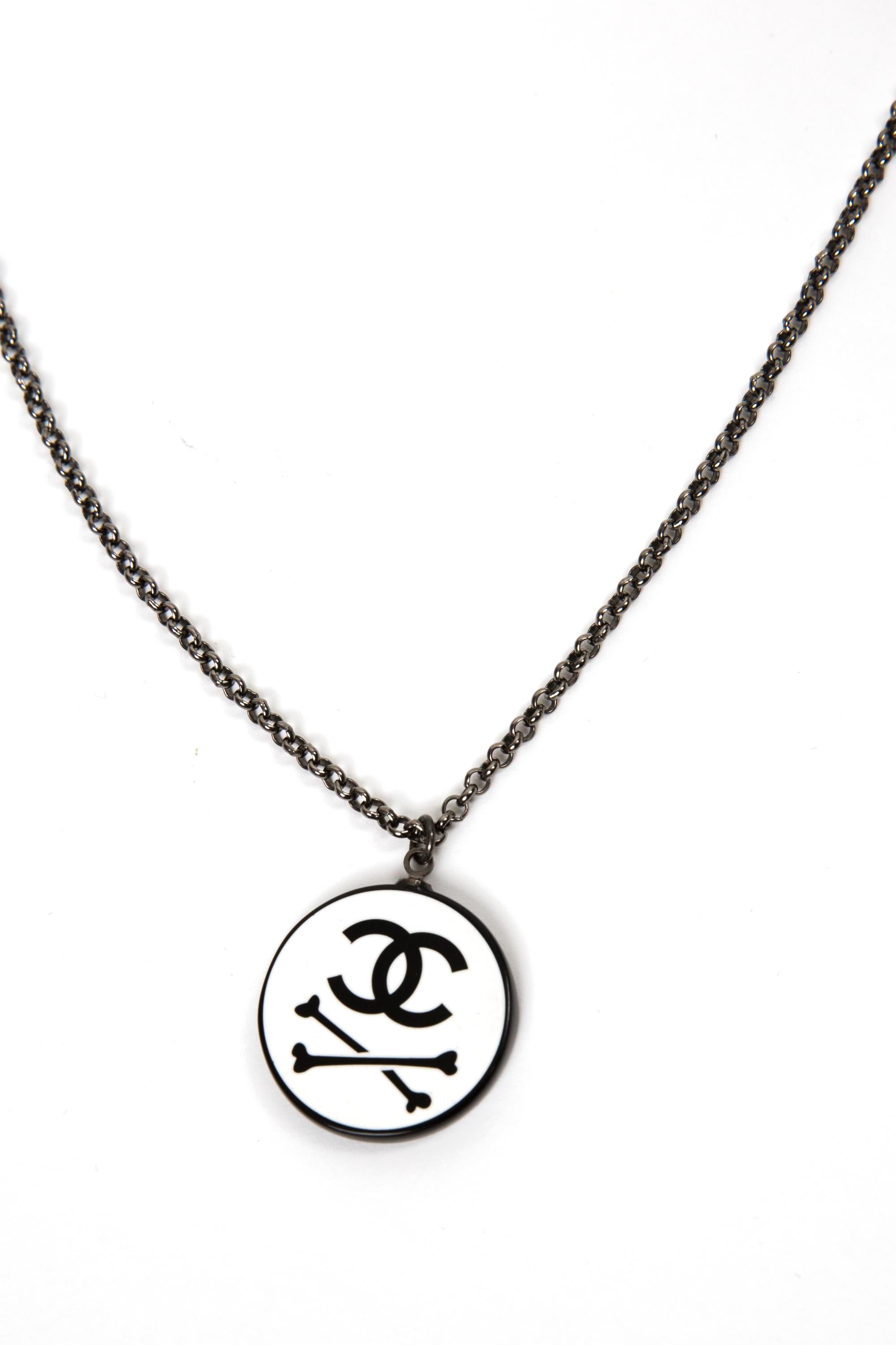 Chanel Black Logo & bones necklace featuring a thin chain, a center medal with black bones and a signature interlocking CC logo, a lobster claw fastening, plaque pitted at chain end. 
Circa 2010 . Made in France
Maxi Length: 18.1in. (46cm)
Good 