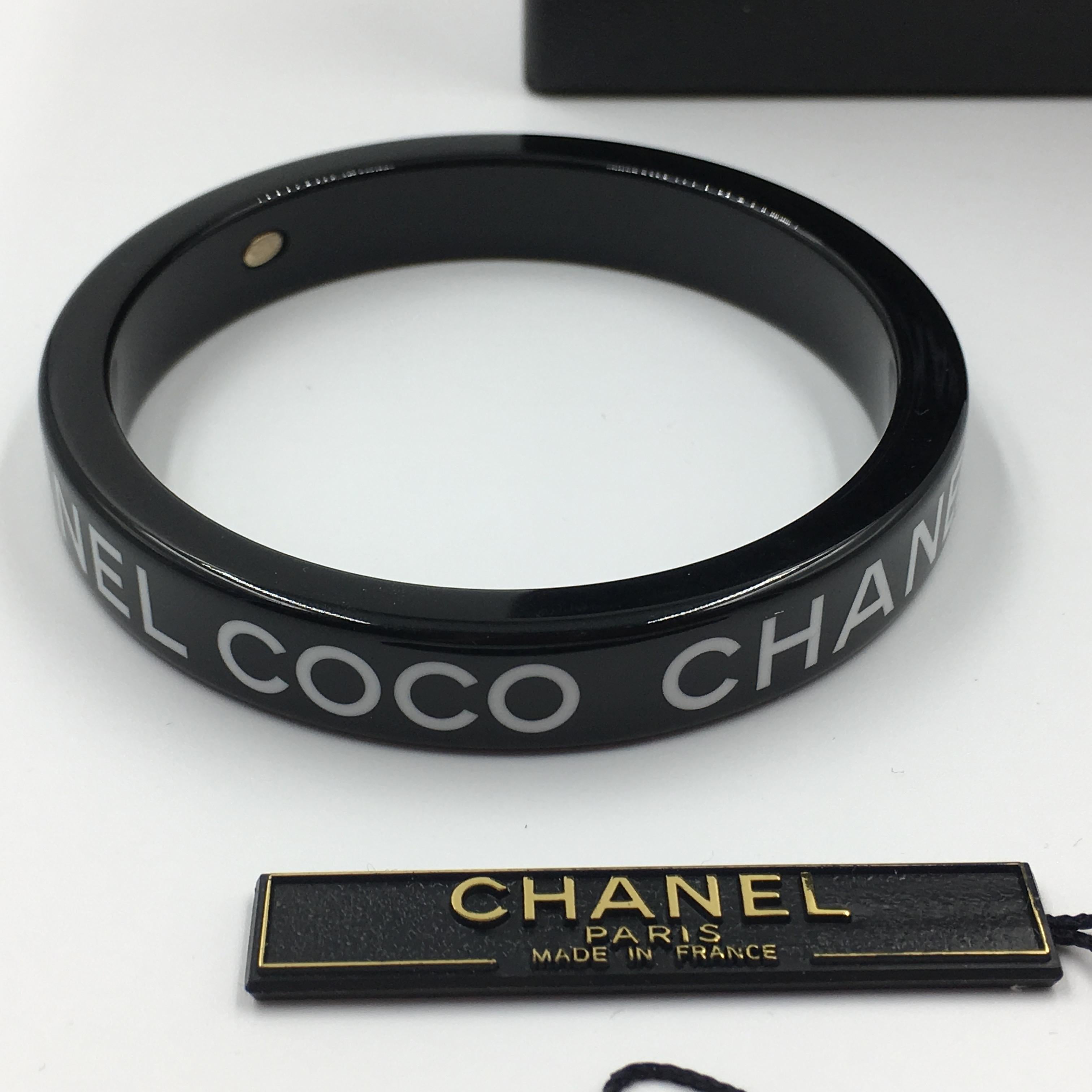 Chanel Black Logo Bangle - Continual name printed along entire bangle- Coco Chanel Coco Chanel Coco Chanel. Stamped Chanel inside. Made in France.
In very good vintage condition. 

Measurements are as follows:

Outer width- 3
