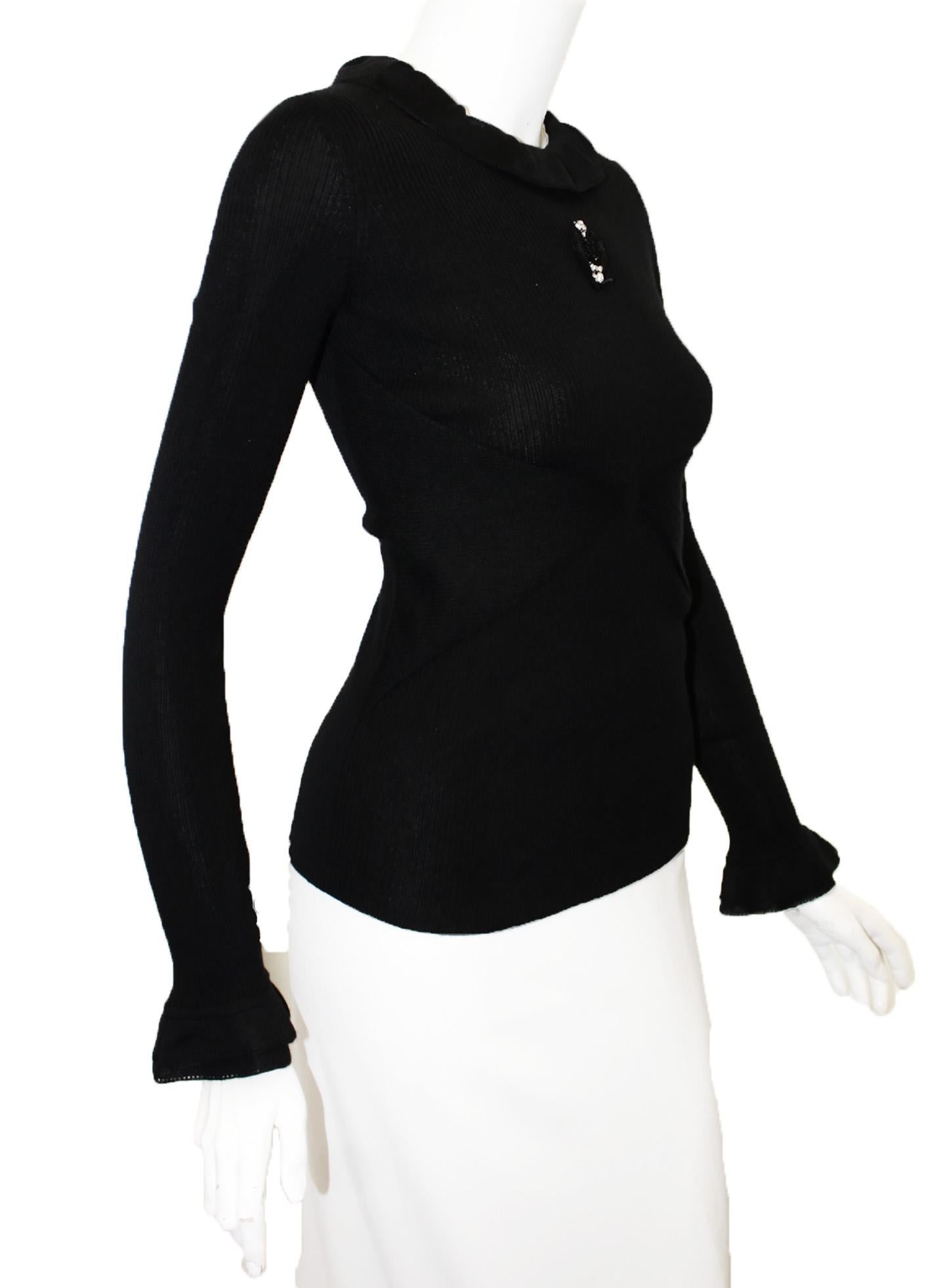 Chanel black long sleeve lightweight cashmere top incorporates a ruffled collar, and, ruffled cuffs.  With knit panels at the waist that unite at center of top.  Includes a grosgrain medallion with interlocking CC embellished in black and clear