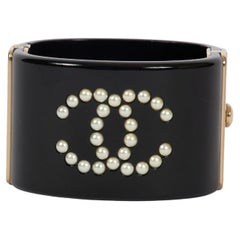 Bracciale rigido Chanel in lucite nera con cerniera e logo con perle
