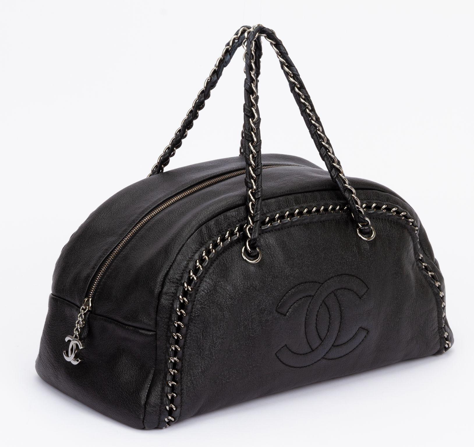 Chanel Luxe Ligne Bowler Bag in black. The is crafted of calfskin leather and featuring tonal top stitching and interlocking 'CC' embroidery on front, finished with woven silver-tone chain-link hardware. The drop of the handle is 7.5