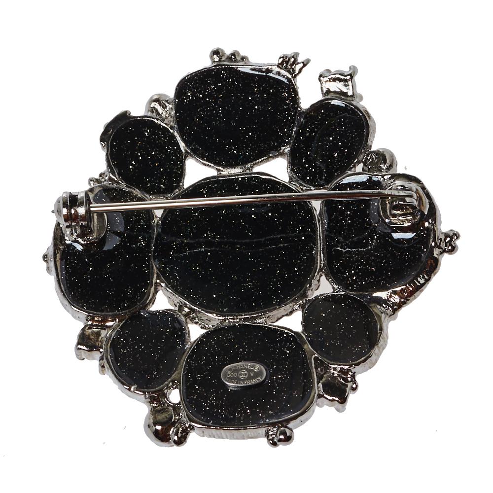 How exquisite is this Chanel brooch! It has been crafted from silver-tone metal and inlaid with metallic black resin beads that look absolutely eye-catching. The brooch flaunts the iconic CC logo in the center and is equipped with a pin closure at