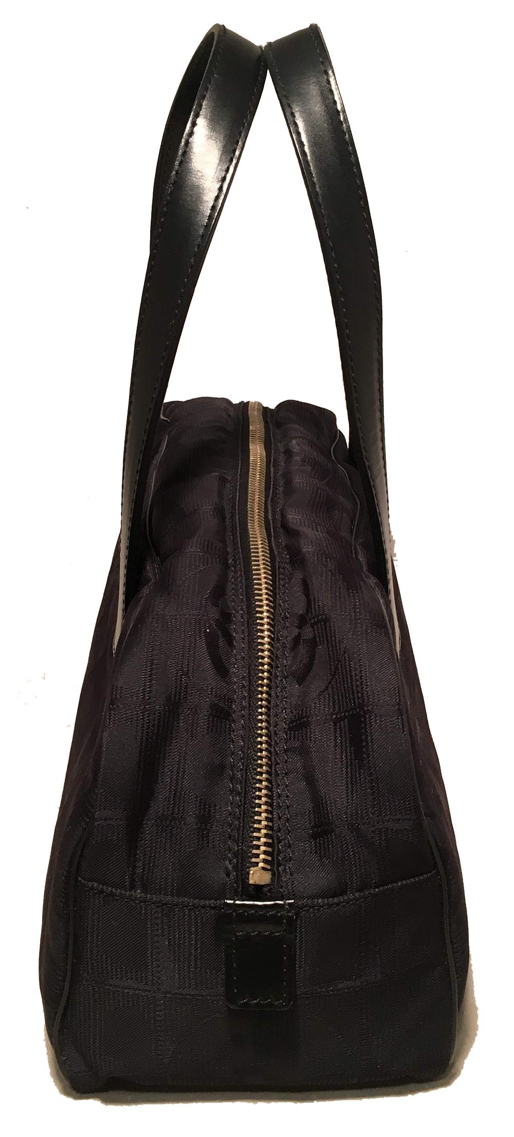 Chanel schwarze Nylon Reisetasche in ausgezeichnetem Zustand. Schwarzer, geprägter Nylonkörper mit schwarzen Ledergriffen, paspelierten Kanten, goldenem Reißverschluss und 4 Füßen am Boden. Innenraum aus Nylon mit einer Seitentasche mit