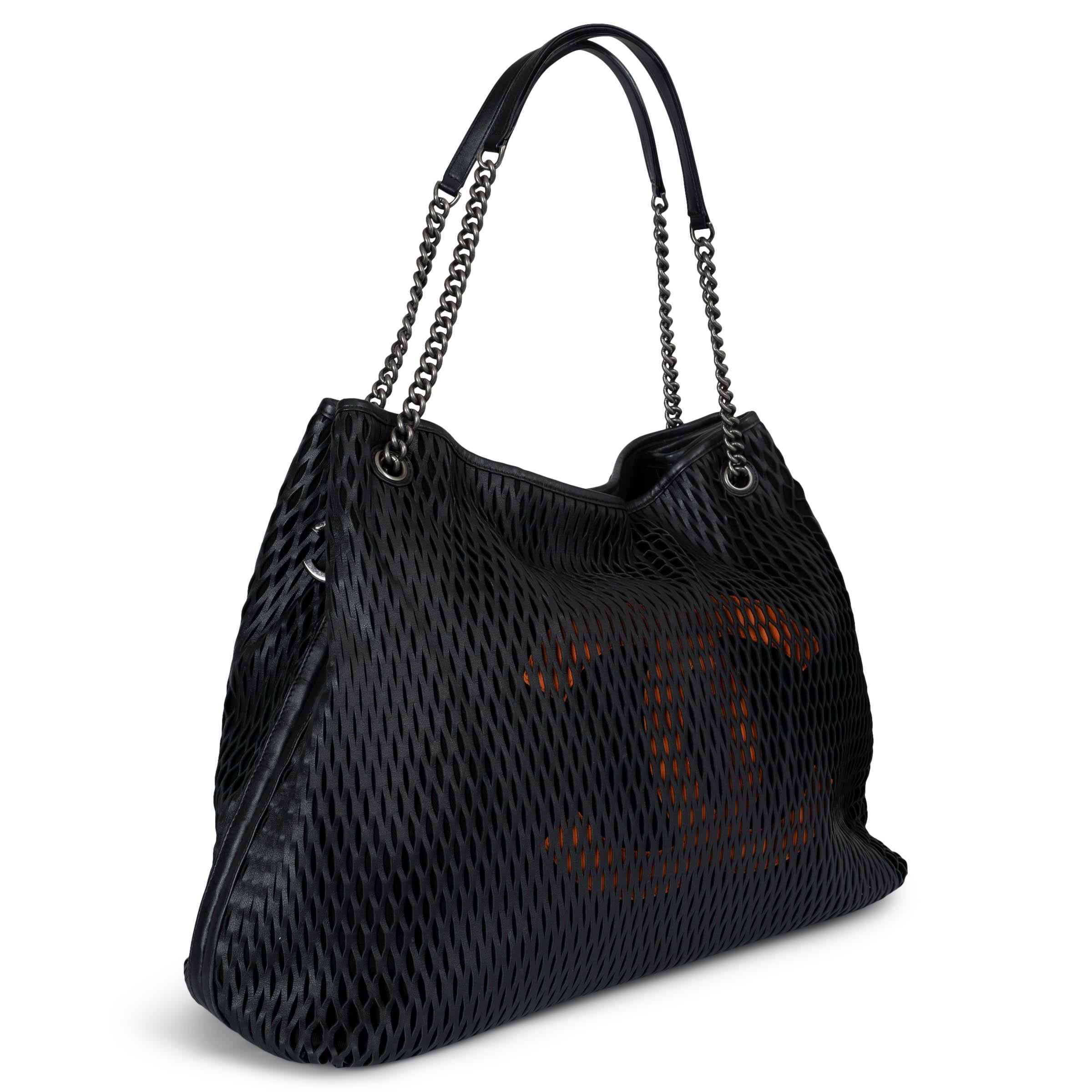 This 100% authentic Chanel Black Laser Cut Perforated Leather CC Tote Bag is a stunning collectible piece. Crafted from black laser-cut leather over canvas, it reveals a subtle orange CC logo underneath for a unique pop of color. The bag features