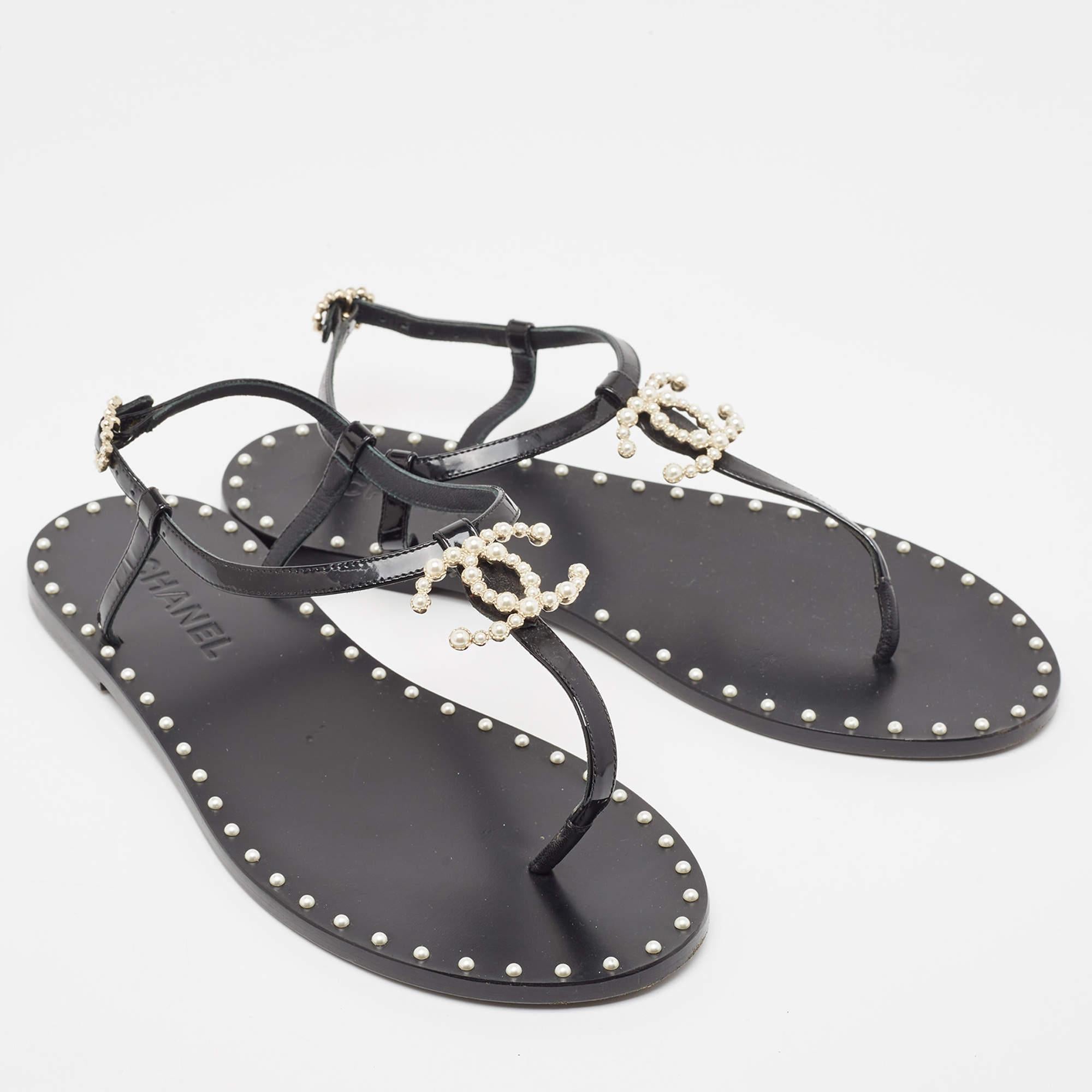 This season, give the Chanel touch to your outfit by stepping out in these sandals. Crafted from black patent leather, this pair features a thong design and buckle fastening at the ankles. The pair is complete with an embellished CC logo on the