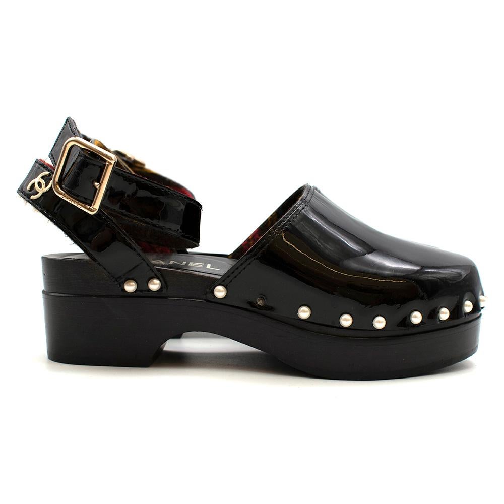 Chanel Patent Black Clogs

- Shiny patent style 
- Embellished with faux-pearls around the edges
- Slight platform heel
- Lined with tartan fabric 
- Gold buckle on the ankle
- Wooden heel 
- CC in gold on the ankle strap
- Quilted sole signature
