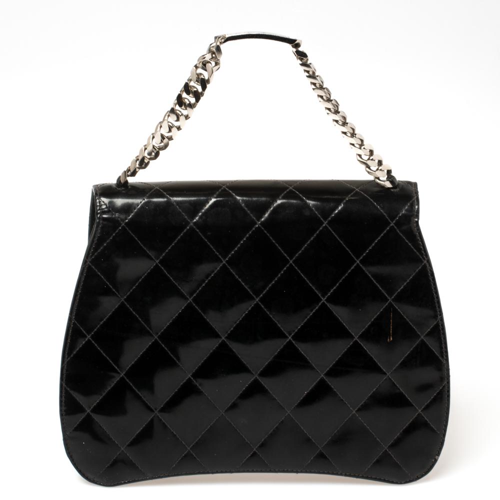 This flap bag by Chanel is a petite beauty with an understated charm and winsome appeal. The signature quilted pattern adorns its black patent leather exterior and it is held by a label ID-detailed chainlink strap. The logo-accented front flap opens