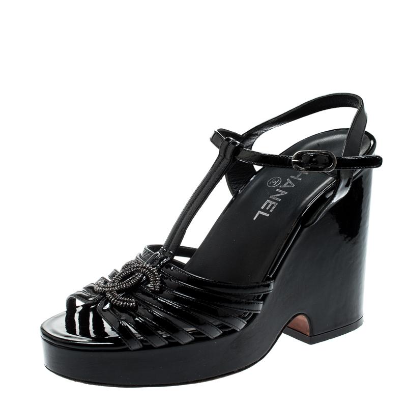 These Chanel sandals are comfortable and gorgeous. Crafted from black patent leather, they feature open toes with sleek straps on the vamps accented with CC logos. The T-straps connect to buckle fastened adjustable ankle straps. The pair is elevated