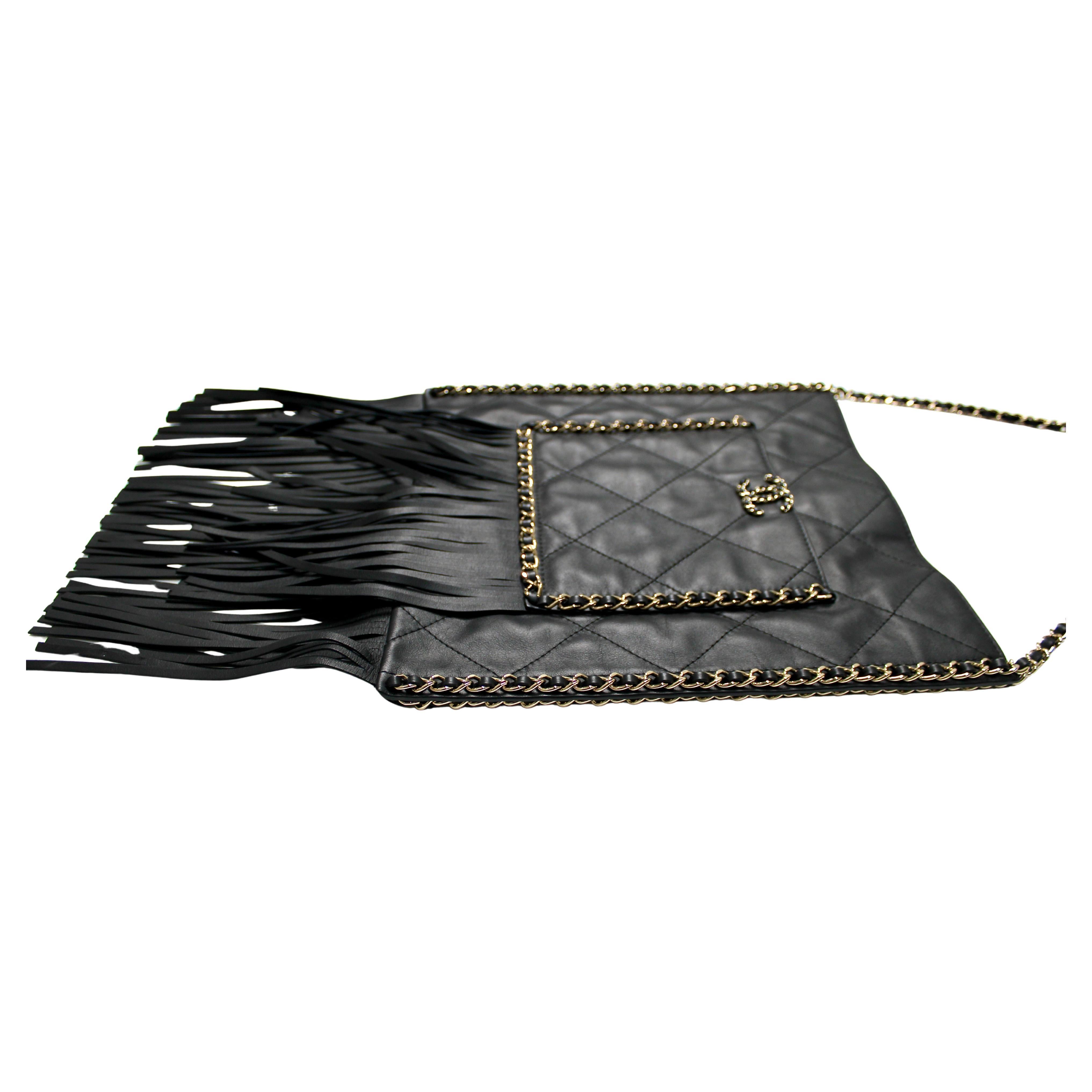 Le sac fourre-tout plat à franges en cuir de veau matelassé noir de Chanel exsude l'élégance intemporelle et la sophistication moderne. Confectionné en luxueux cuir de veau matelassé, ce fourre-tout présente une silhouette élégante et structurée aux
