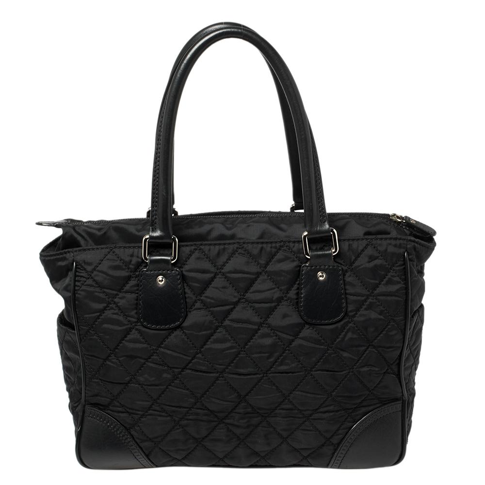 Give your wardrobe an instant elegant boost with this stunning tote from Chanel. It has been crafted from black fabric and leather in the signature quilt design and features dual handles, silver-tone hardware detailing, and protective metal feet.