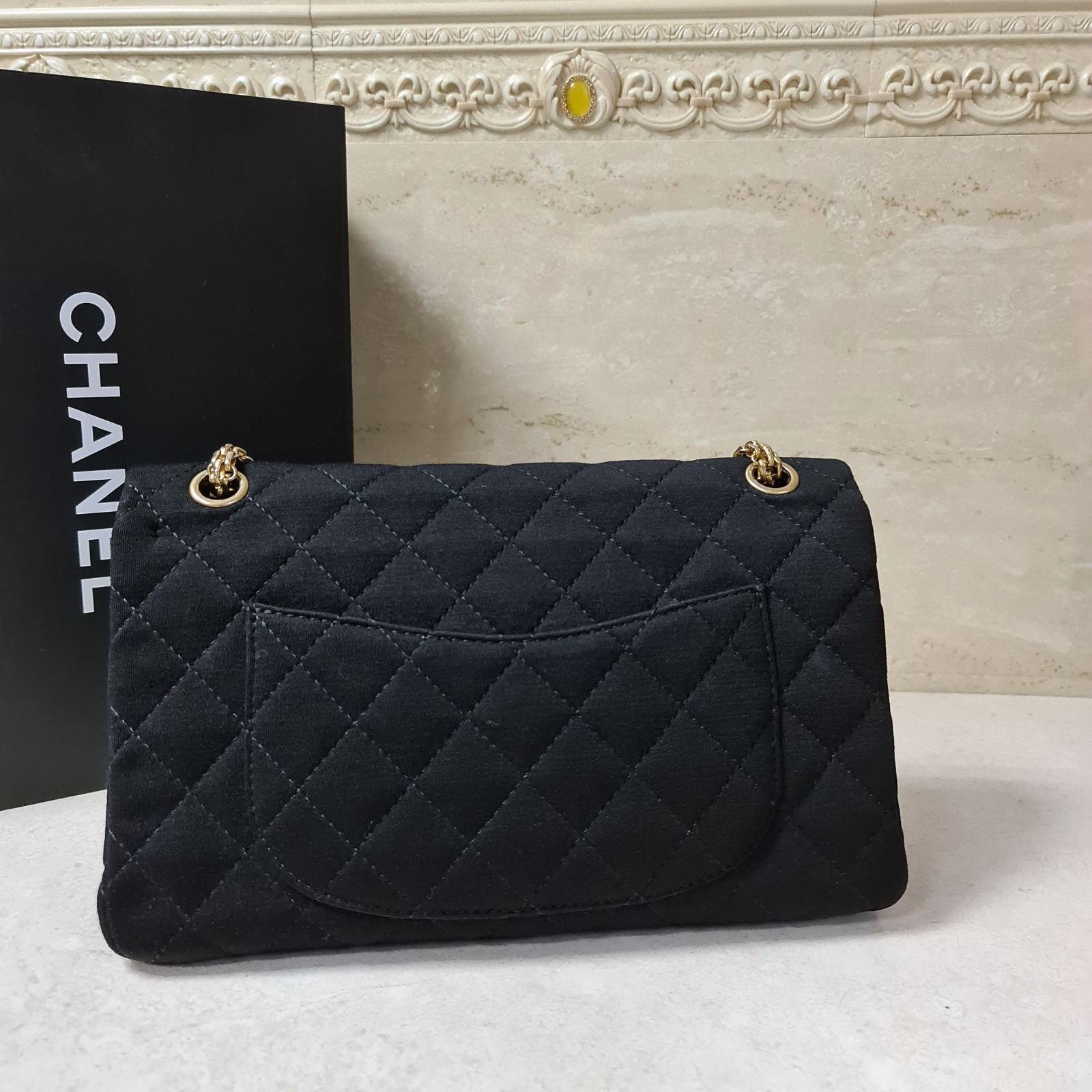 Exquisitely crafted from black fabric, this Reissue 2.55 flap bag from Chanel has the signature mademoiselle lock on the flap closure. It has a quilted pattern all over and the piece is complete gold tone hardware, a leather lined interior and a
